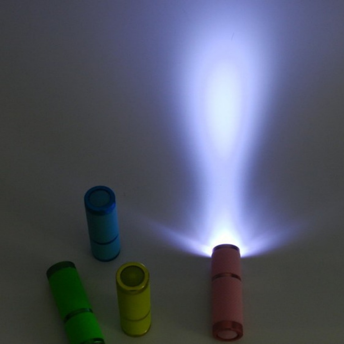 Eine leuchtende rosa Taschenlampe strahlt hell nach oben, umgeben von grünen, gelben und blauen Taschenlampen.