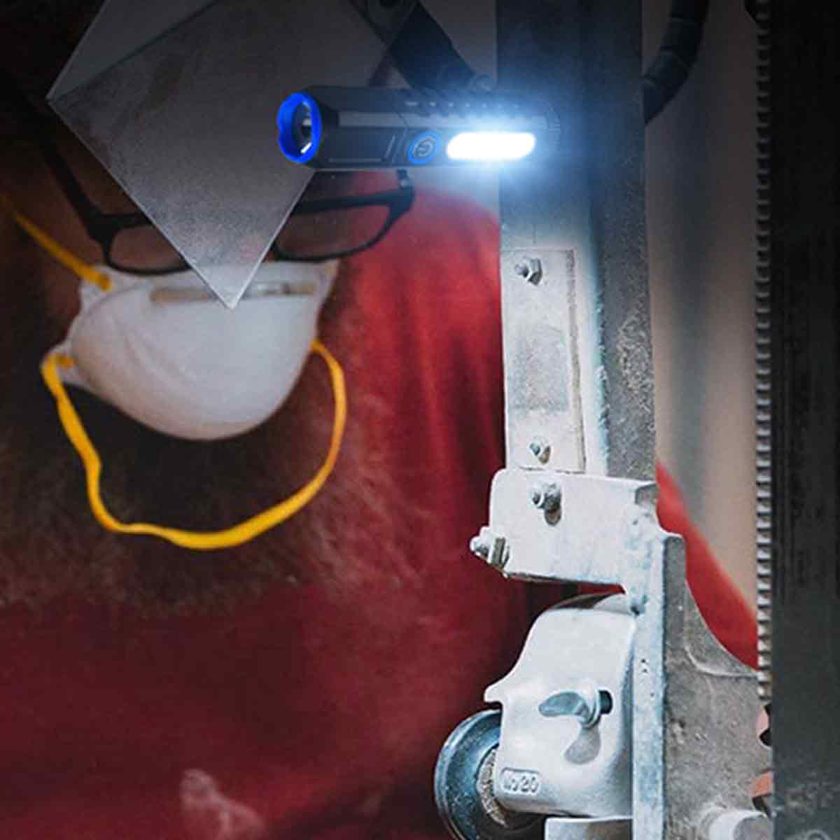 Ein Arbeiter mit Schutzmaske und Brille nutzt eine helle LED-Lampe an einer Maschine.