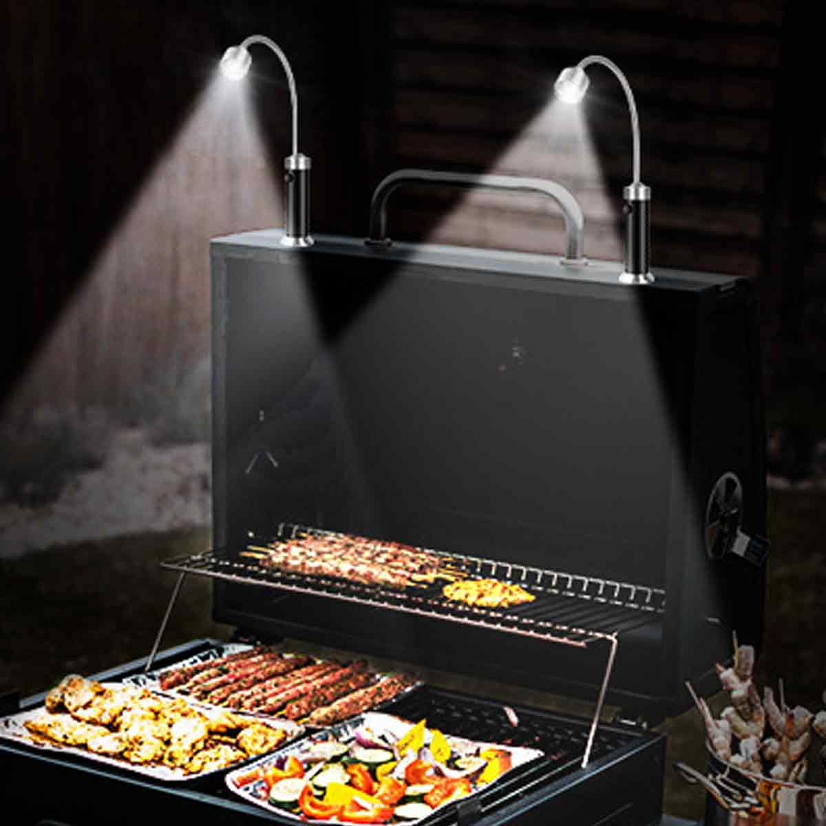 Ein schwarzer Holzkohlegrill nachts, beleuchtet durch zwei flexible LED-Lampen auf der Haube, mit Essen.