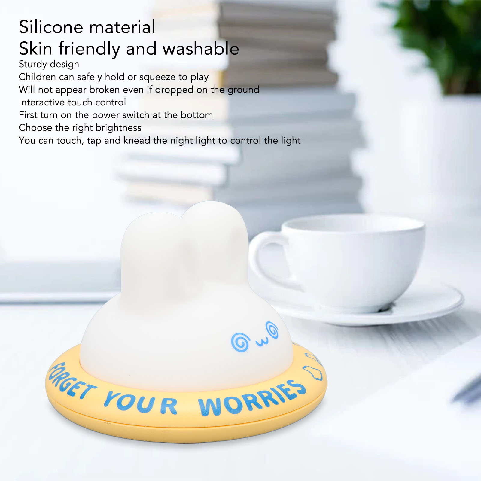 Eine weiße Nachtlampe mit gelbem Sockel steht auf einem Schreibtisch vor einer Tasse und stapelten Büchern.