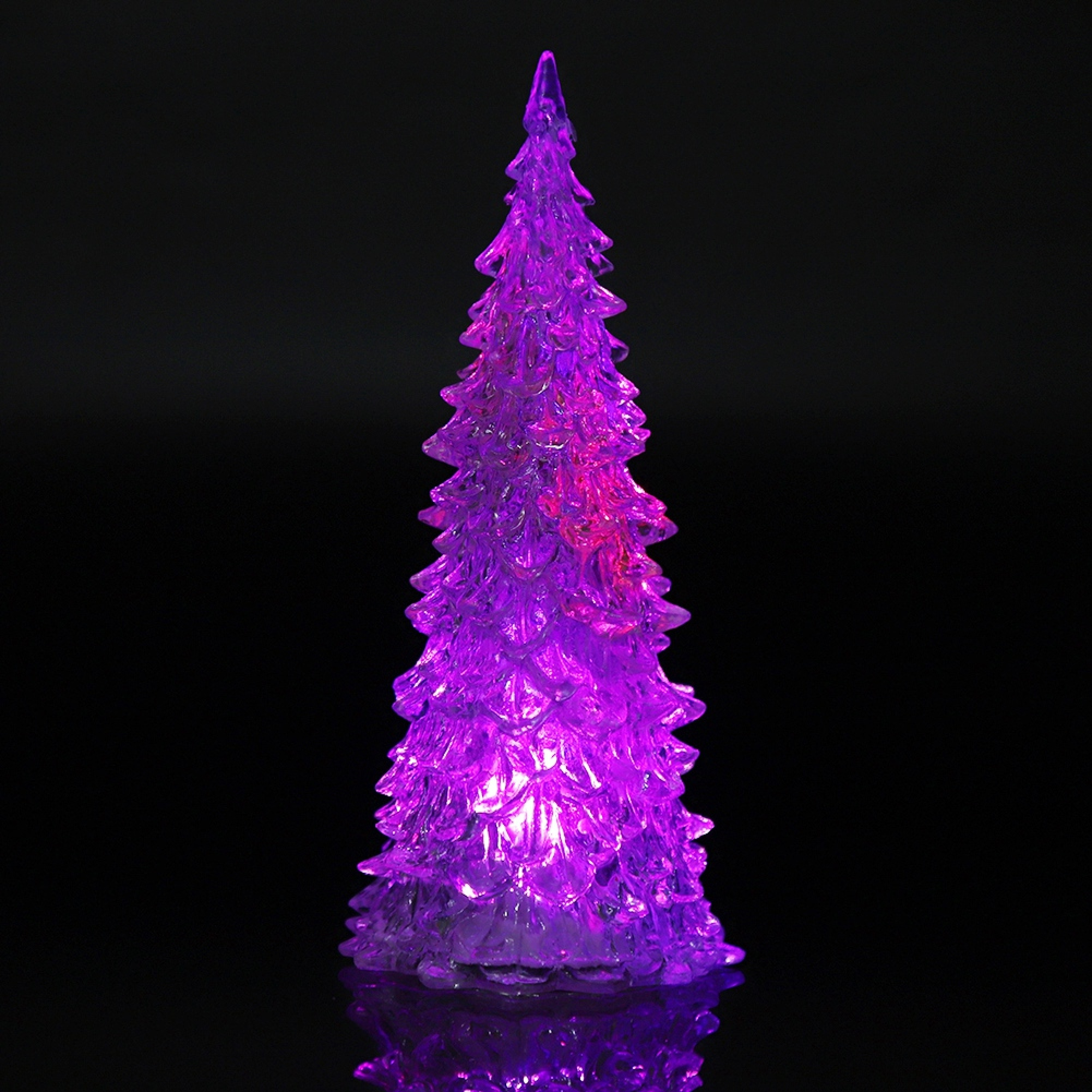 Ein glänzender, lila beleuchteter Weihnachtsbaum aus Glas vor schwarzem Hintergrund.
