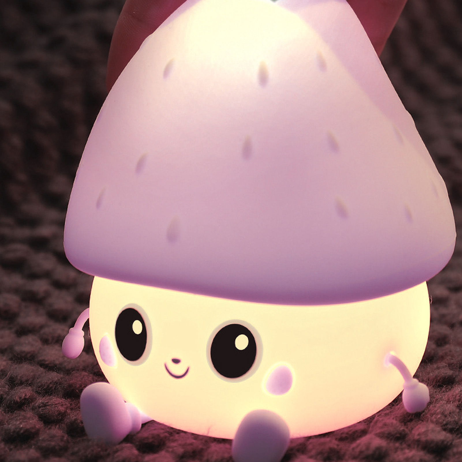 Eine süße, leuchtende Pilz-Nachtlampe mit Gesicht sitzt auf einer Decke.