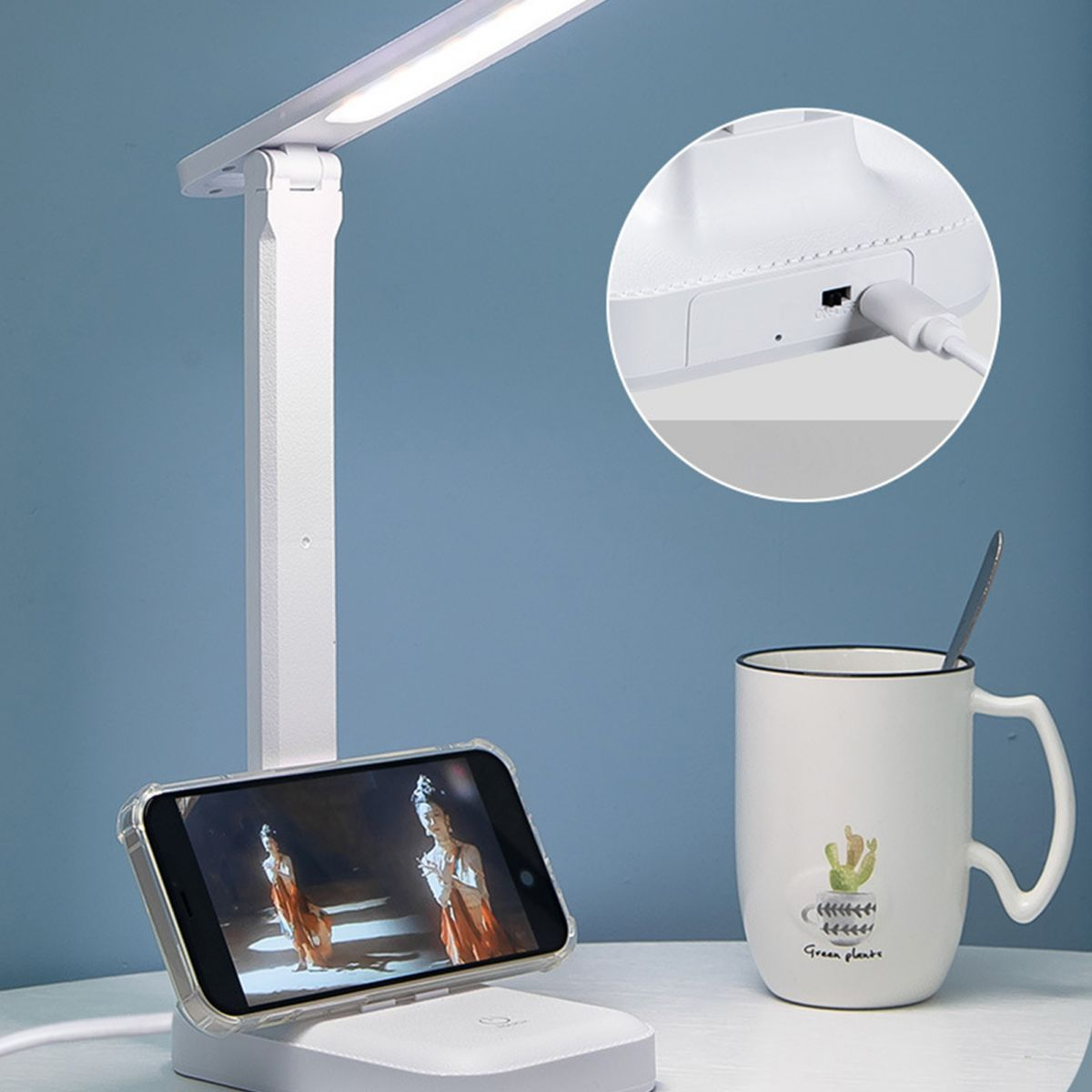 Eine weiße LED-Schreibtischlampe mit Handyhalterung und einer Kaffeetasse daneben; oben rechts ein Detail der Ladebuchse.