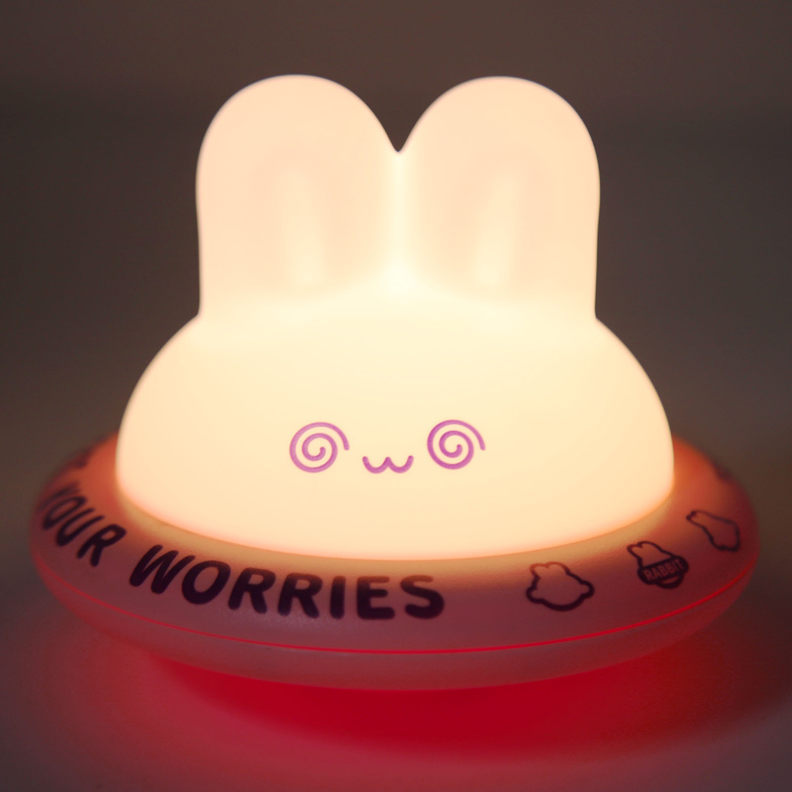 Beleuchtetes Hasen-Nachtlicht mit dem Text 'Our Worries' auf einem runden Sockel vor dunklem Hintergrund.
