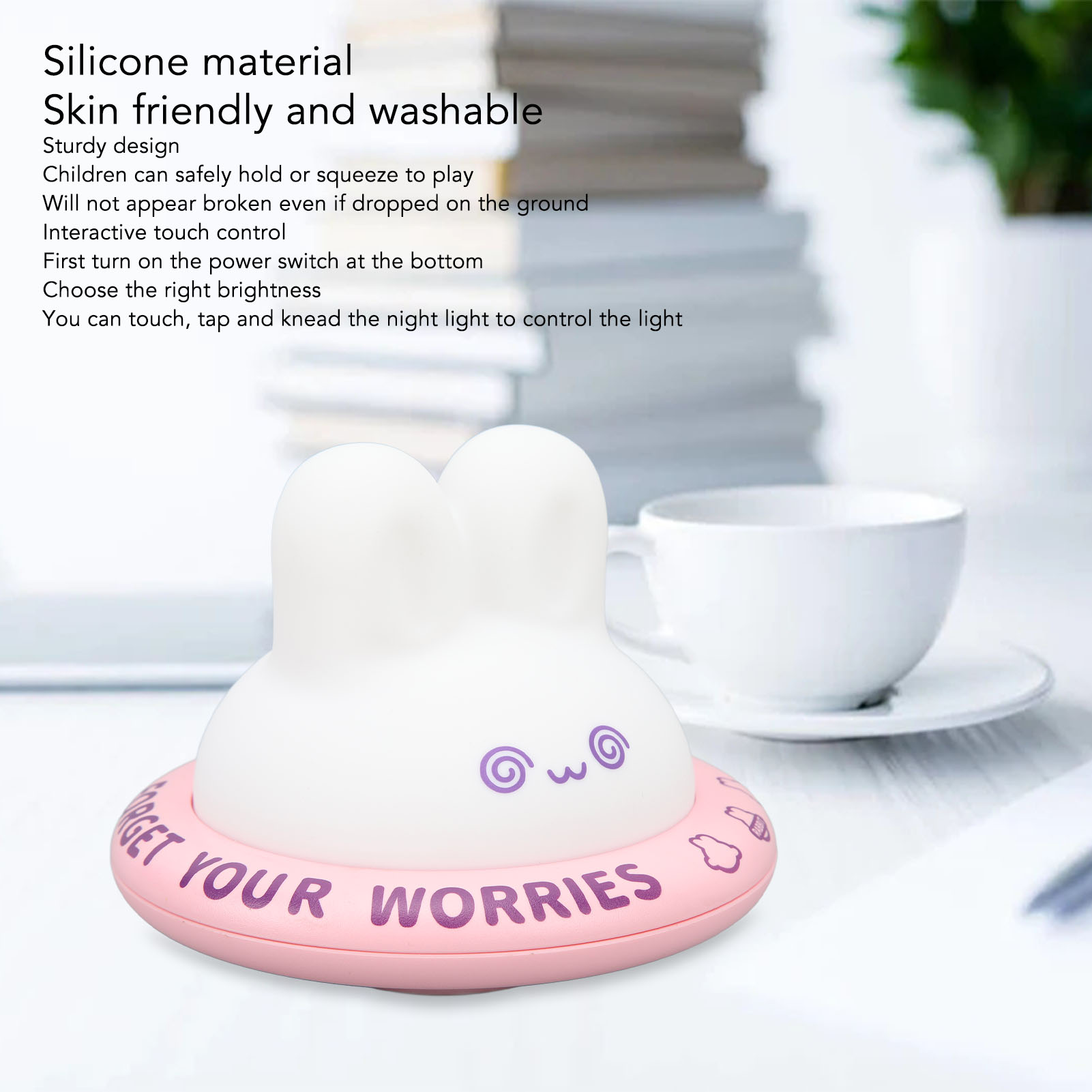 Ein weißes Silikon-Nachtlicht mit Hasenohren auf einer rosa Basis mit der Aufschrift "Forget your worries" auf einem Tisch.