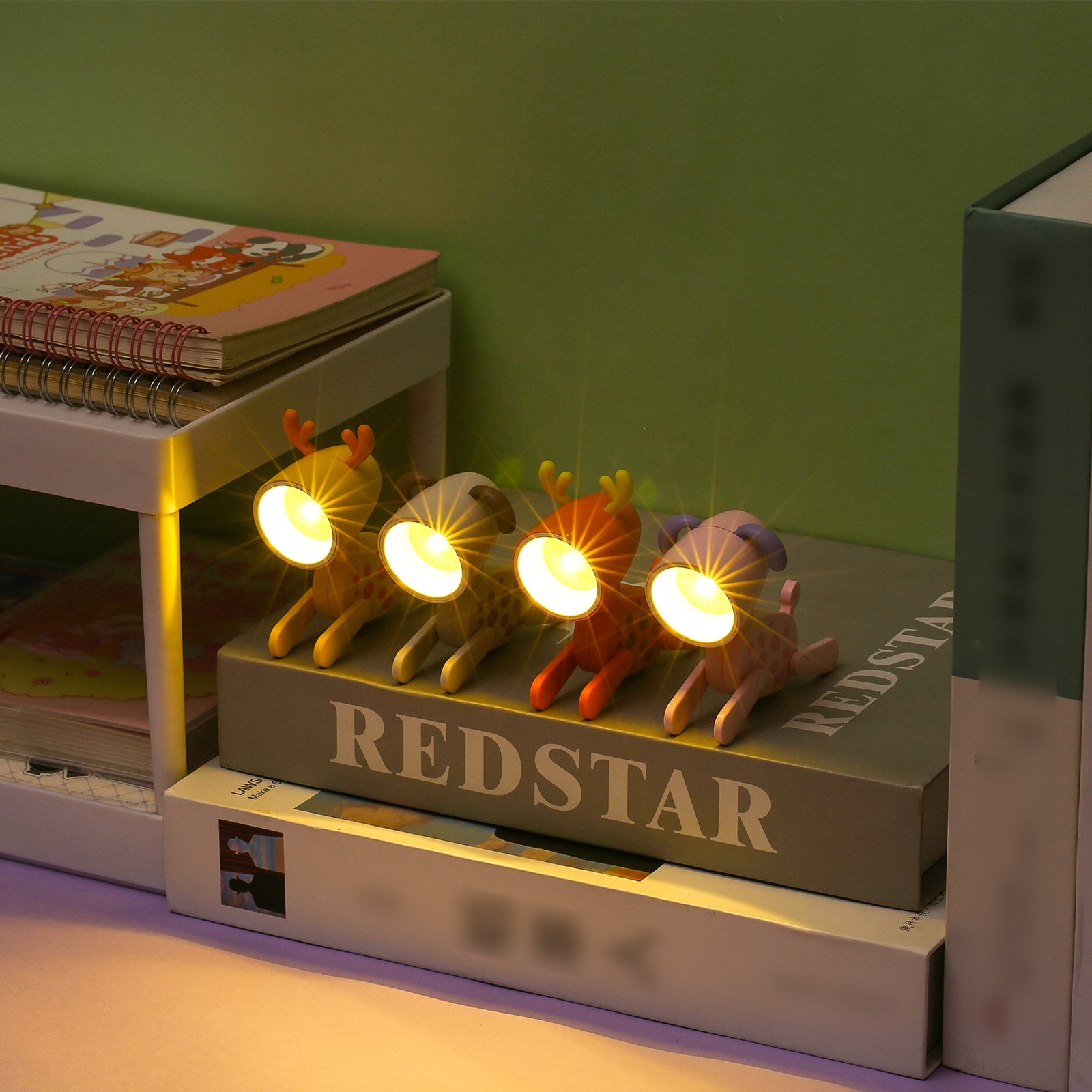 Vier tierförmige Schreibtischlampen mit leuchtendem Licht stehen nebeneinander auf Büchern.