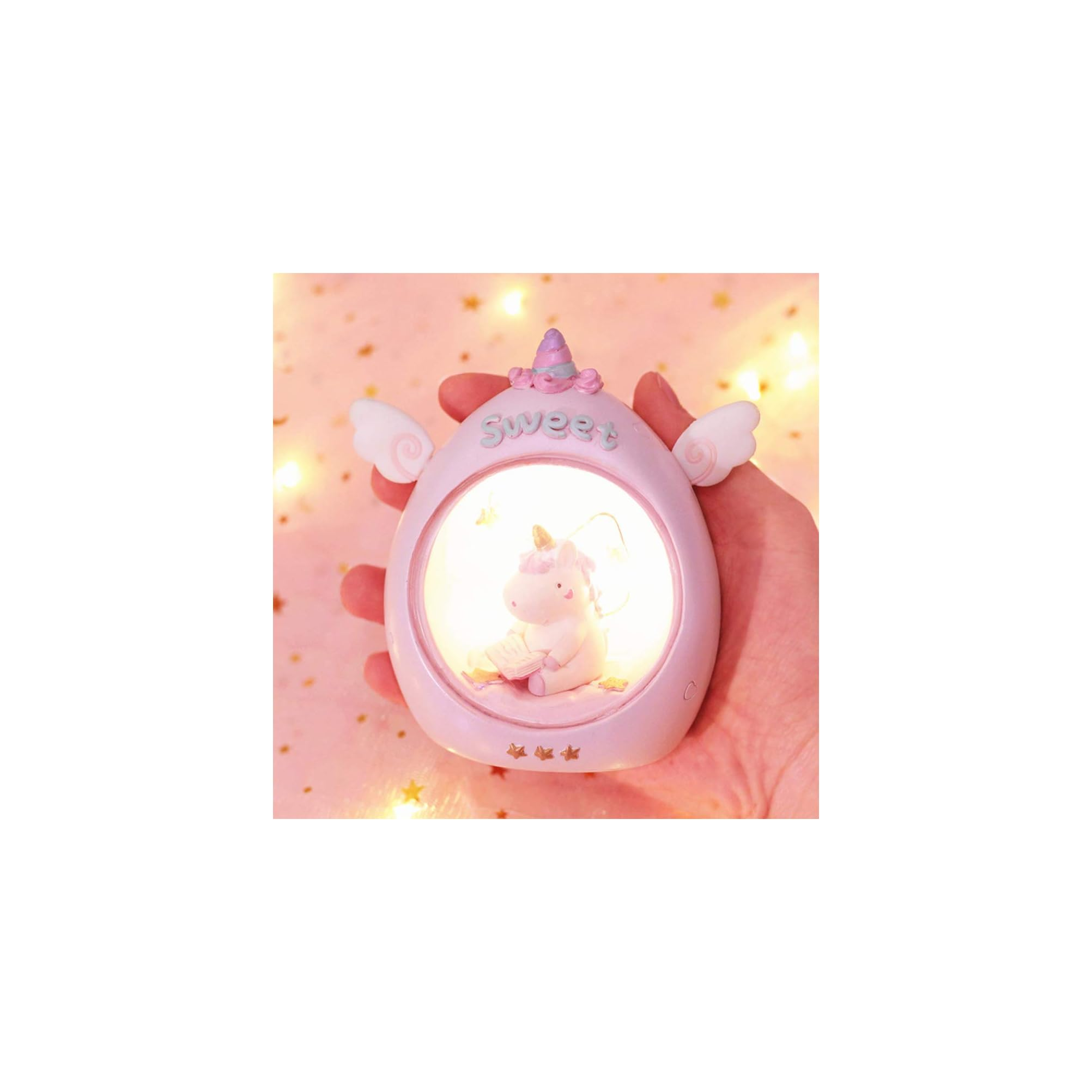 Eine Hand hält eine rosa leuchtende Einhornlampe mit Engelsklügeln.