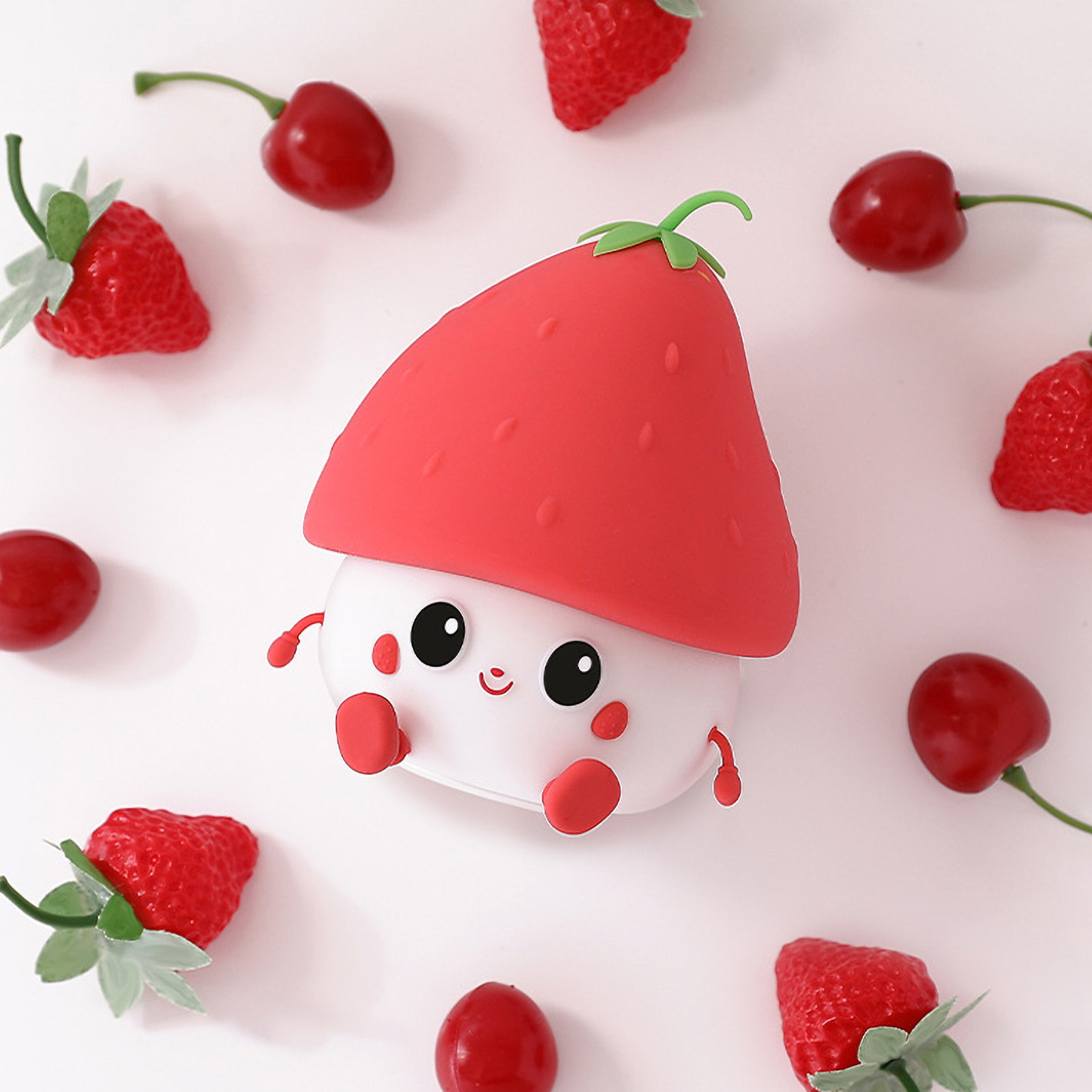 Ein süßer weißer Charakter mit einem roten Erdbeerhut ist von echten Erdbeeren und Kirschen umgeben.