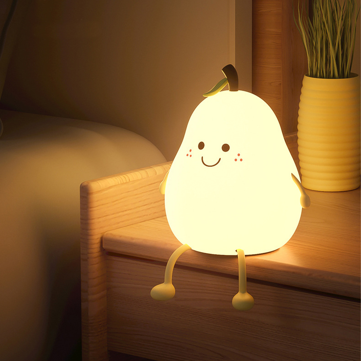 Eine süße, leuchtende Birnenlampe mit Beinen sitzt auf einem Holznachttisch neben einer Pflanze.
