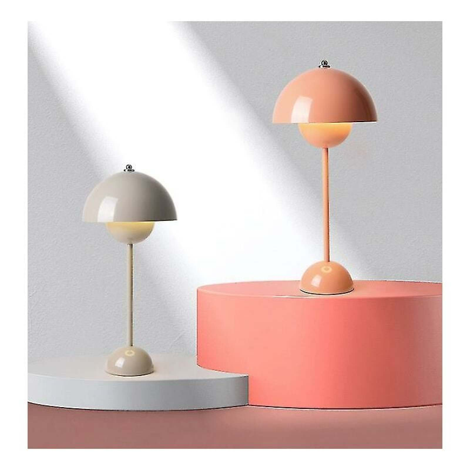 Zwei moderne Tischlampen in Pastellrosa und Grau auf runden Podesten vor einer weißen Wand.
