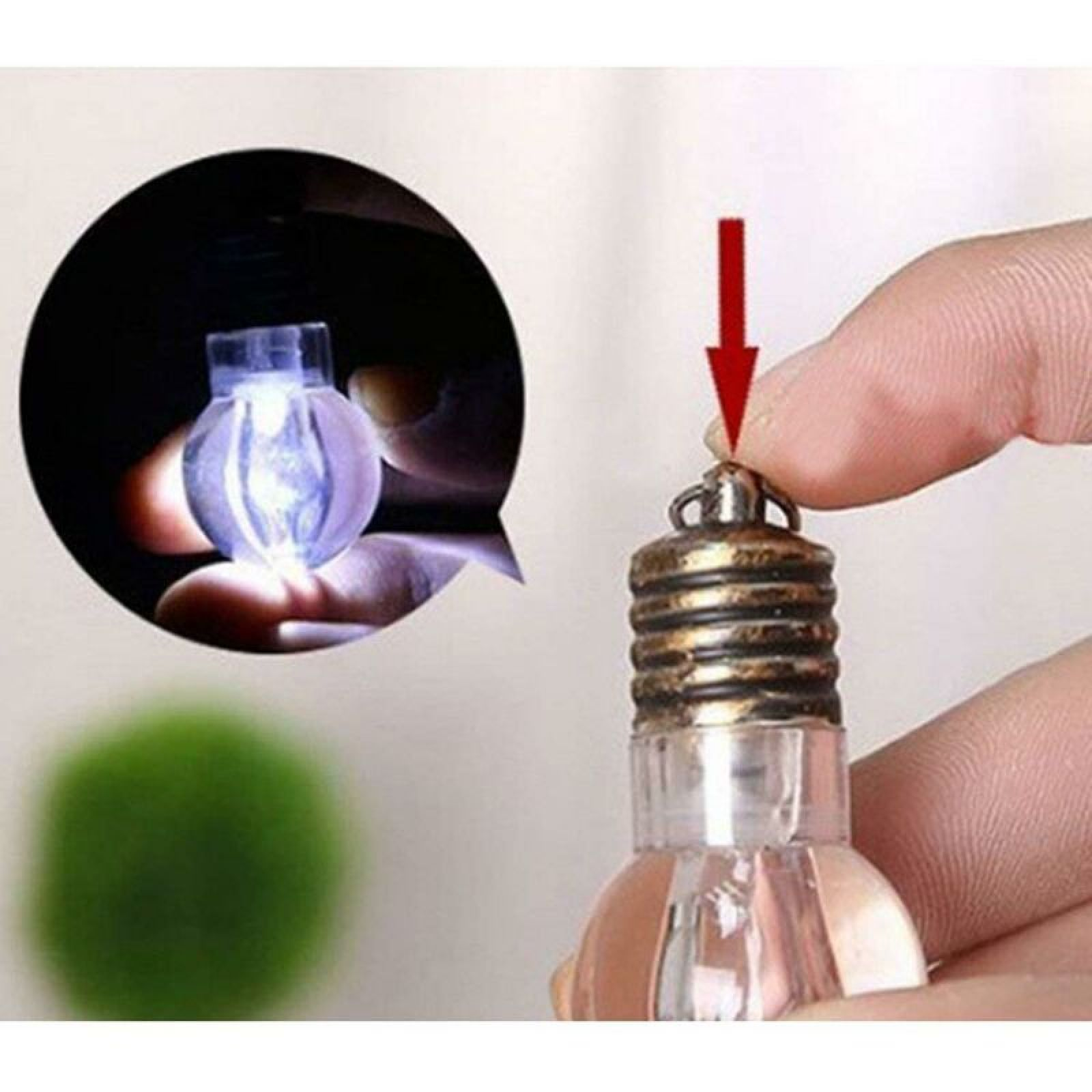 Hand drückt einen kleinen roten Pfeil auf die Metallkappe einer leuchtenden Miniglühlampe.