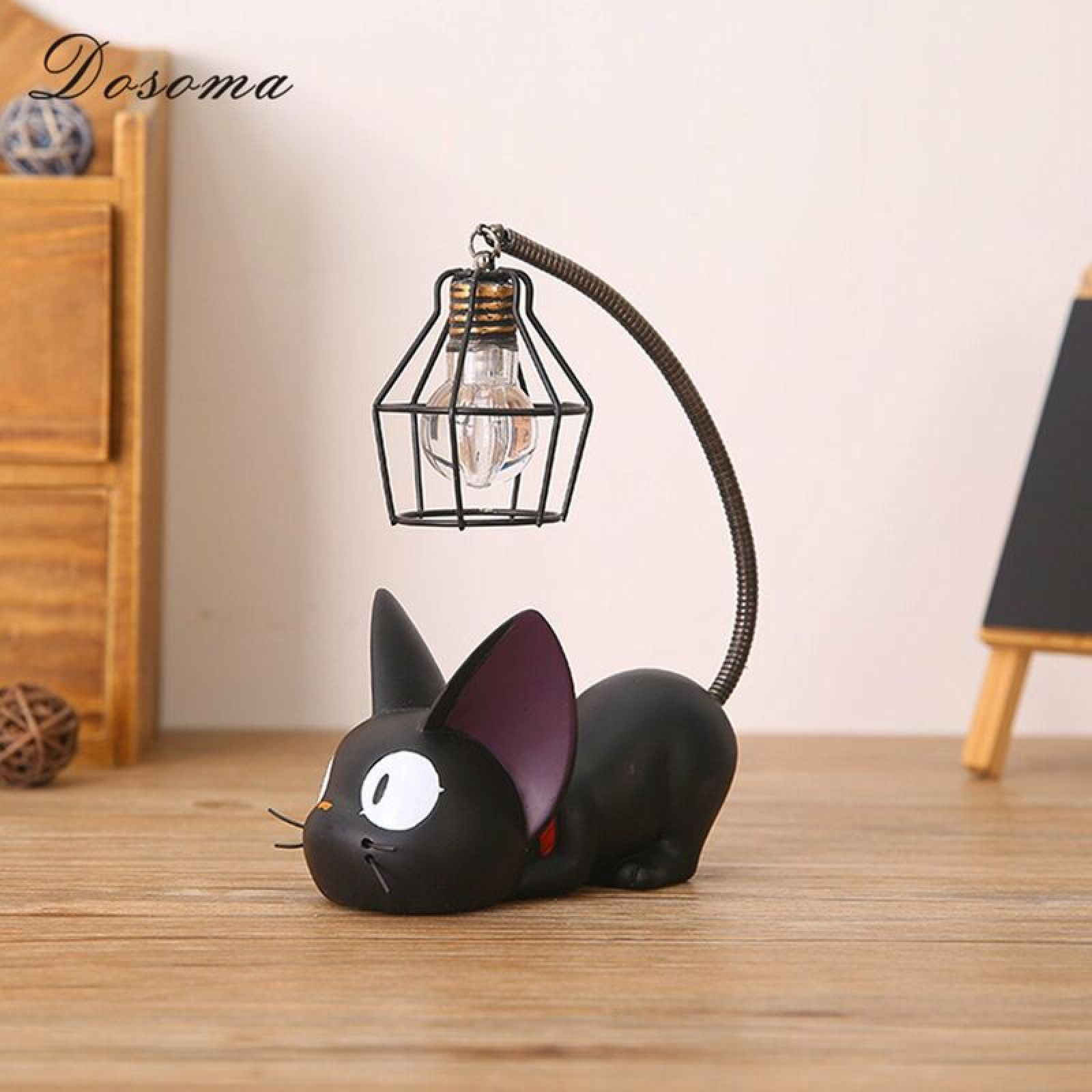Eine schwarze Katzenfigur mit großen weißen Augen und einer Lampe, die wie ein Käfig geformt ist.