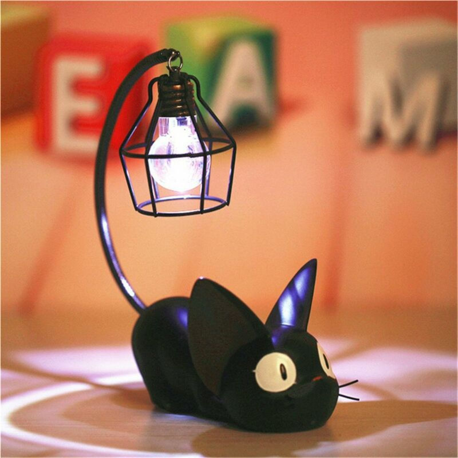 Eine schwarze Katzentischlampe mit einem hängenden Drahtkäfig-Lampenschirm an ihrem gebogenen Schwanz.