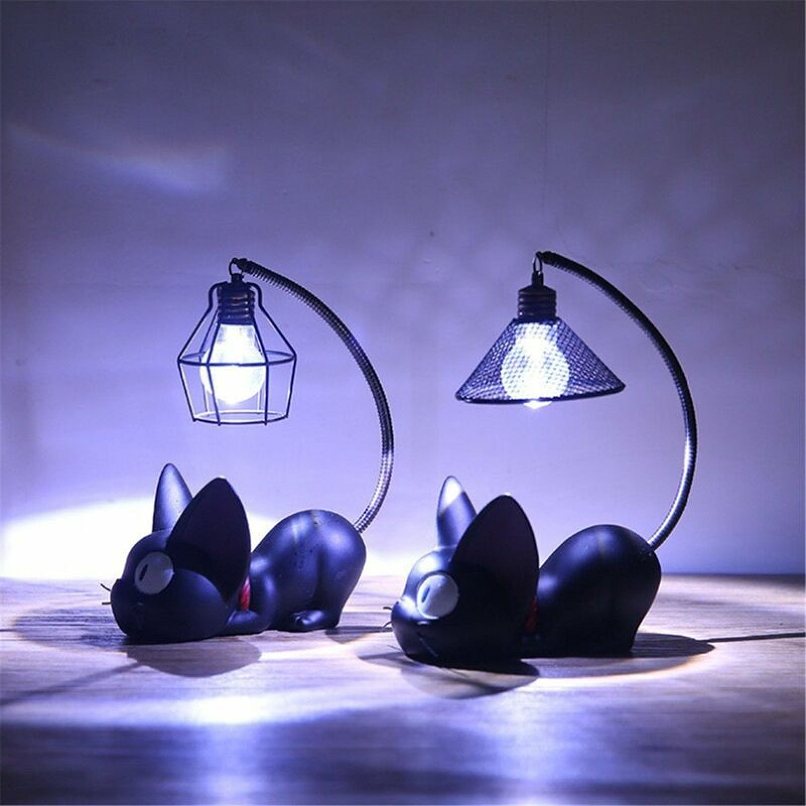 Zwei schwarze katzenförmige Schreibtischlampen mit gebogenen Hälsen stehen auf einer Holzoberfläche.