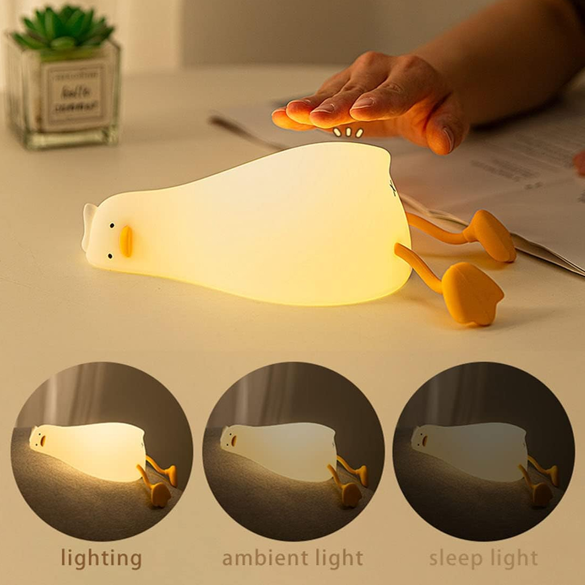 Eine Hand berührt eine weiche, gelbe Enten-Nachtlampe auf einem Tisch.
