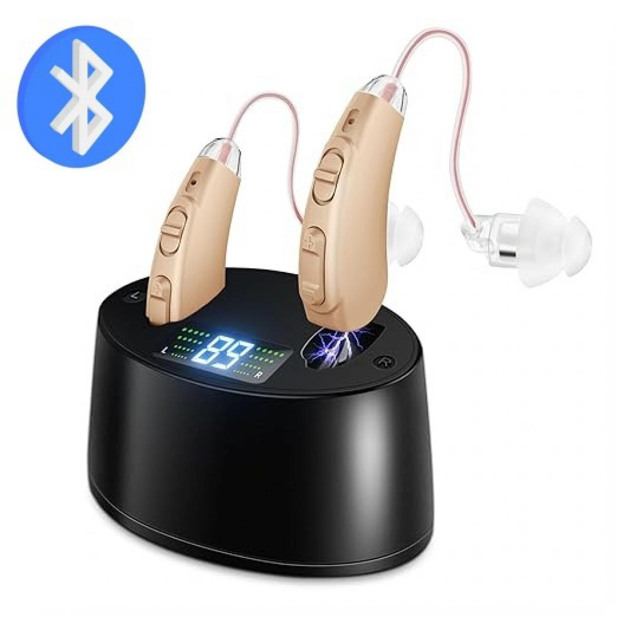 Beige Hörgeräte mit rosa Schläuchen in einer schwarzen Ladestation mit digitaler Prozentanzeige.