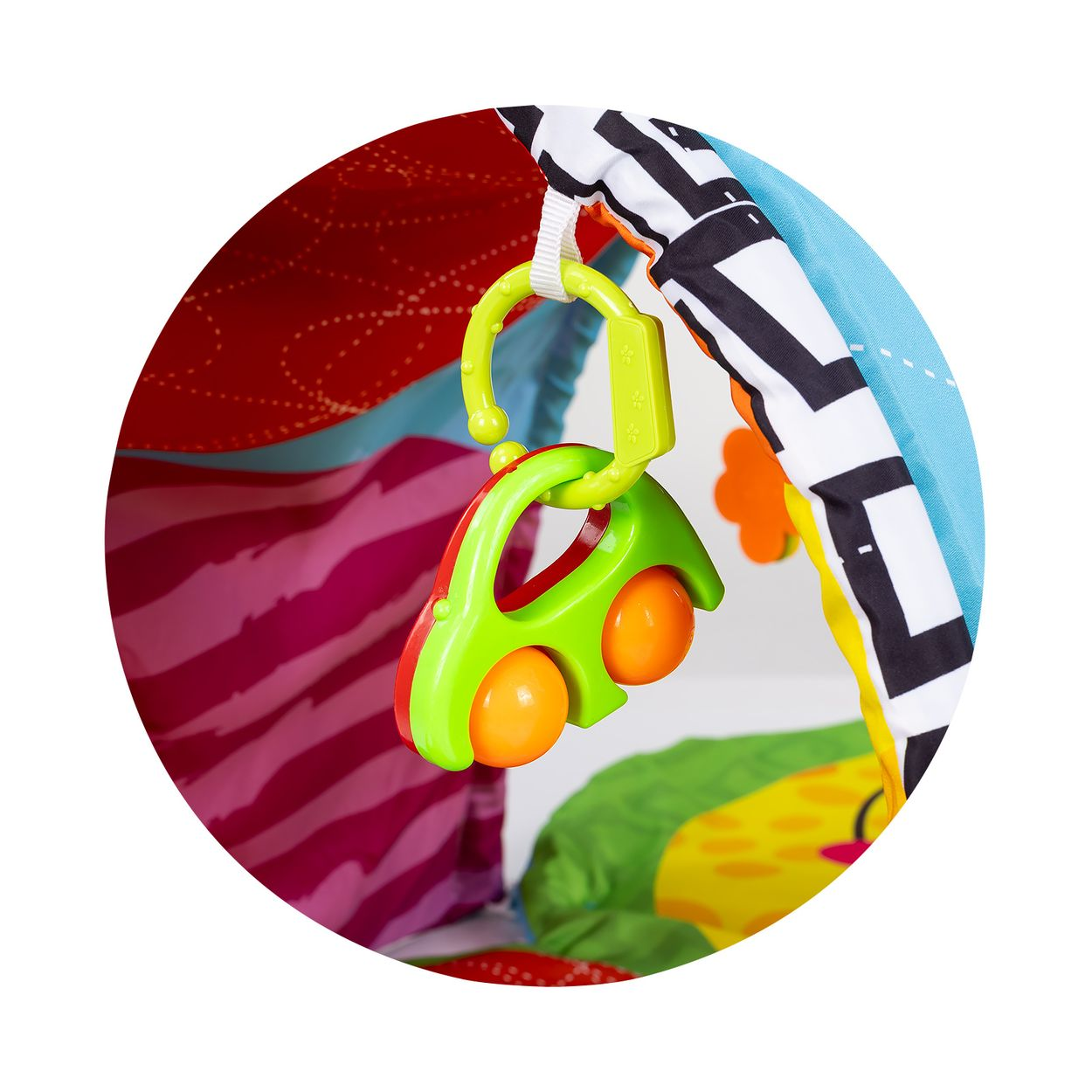 Ein buntes Spielzeugauto hängt von einer farbenfrohen Babydecke.