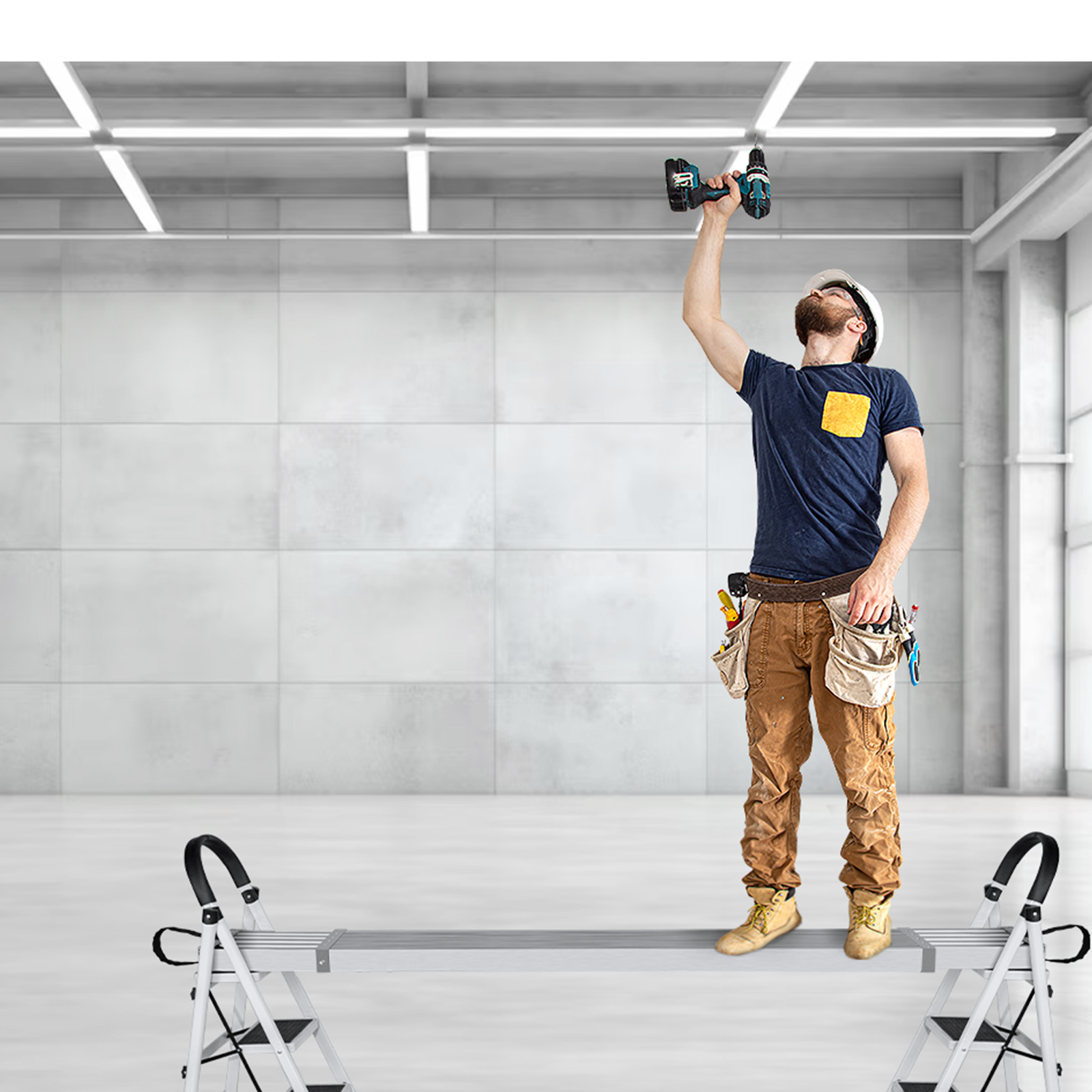 Un trabajador se para en un banco y taladra el techo de una gran sala.