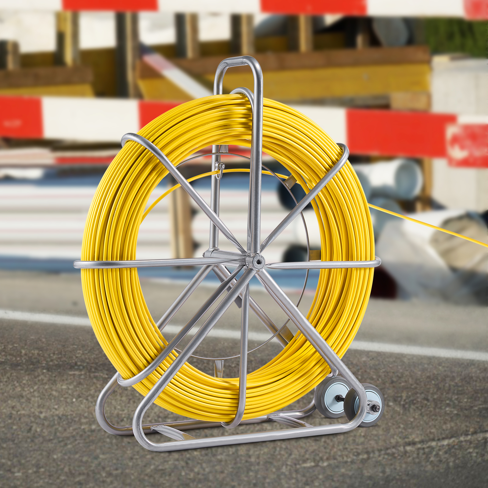 Un gran tambor de cable amarillo en un soporte metálico con ruedas, con una obra al fondo.