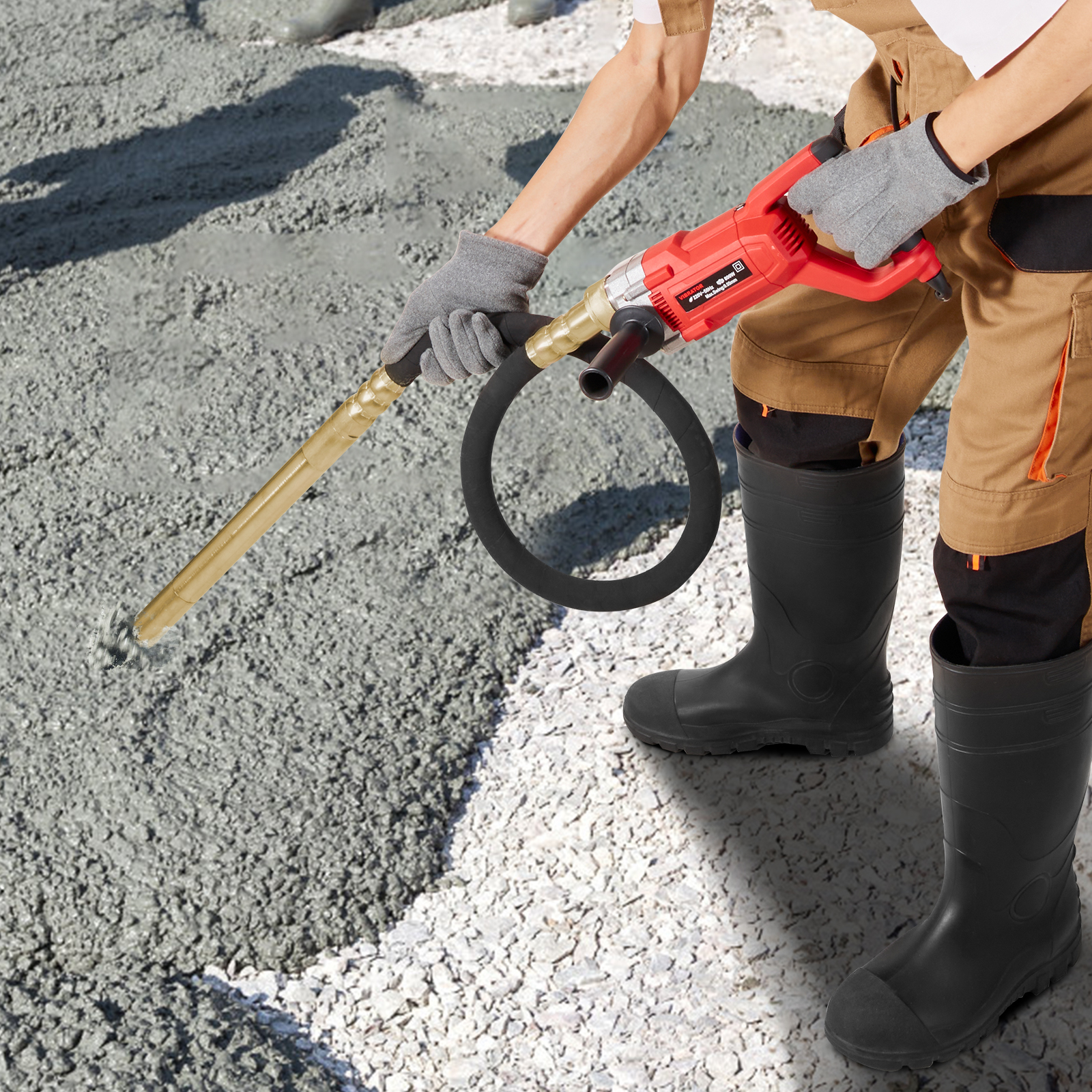 Un trabajador con botas y guantes usa un vibrador de concreto rojo.