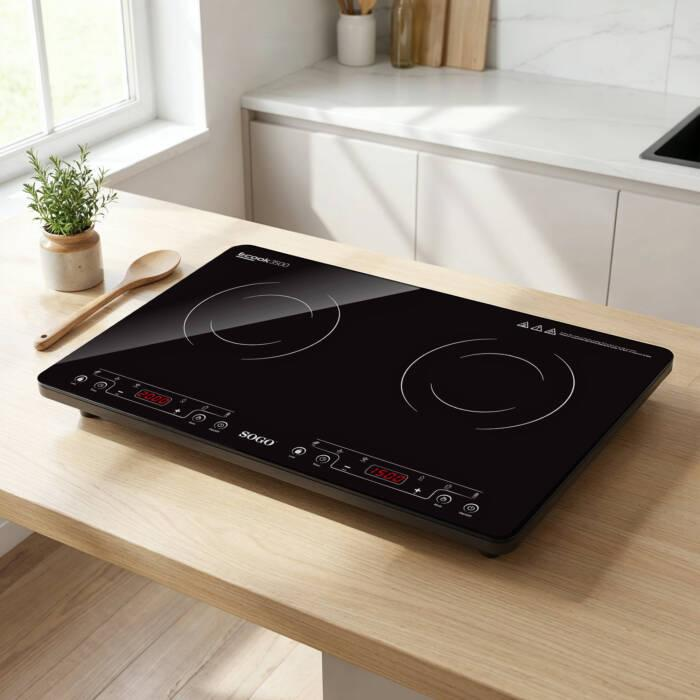 Un piano cottura a induzione nero poggia su un piano di lavoro in legno in una cucina luminosa.