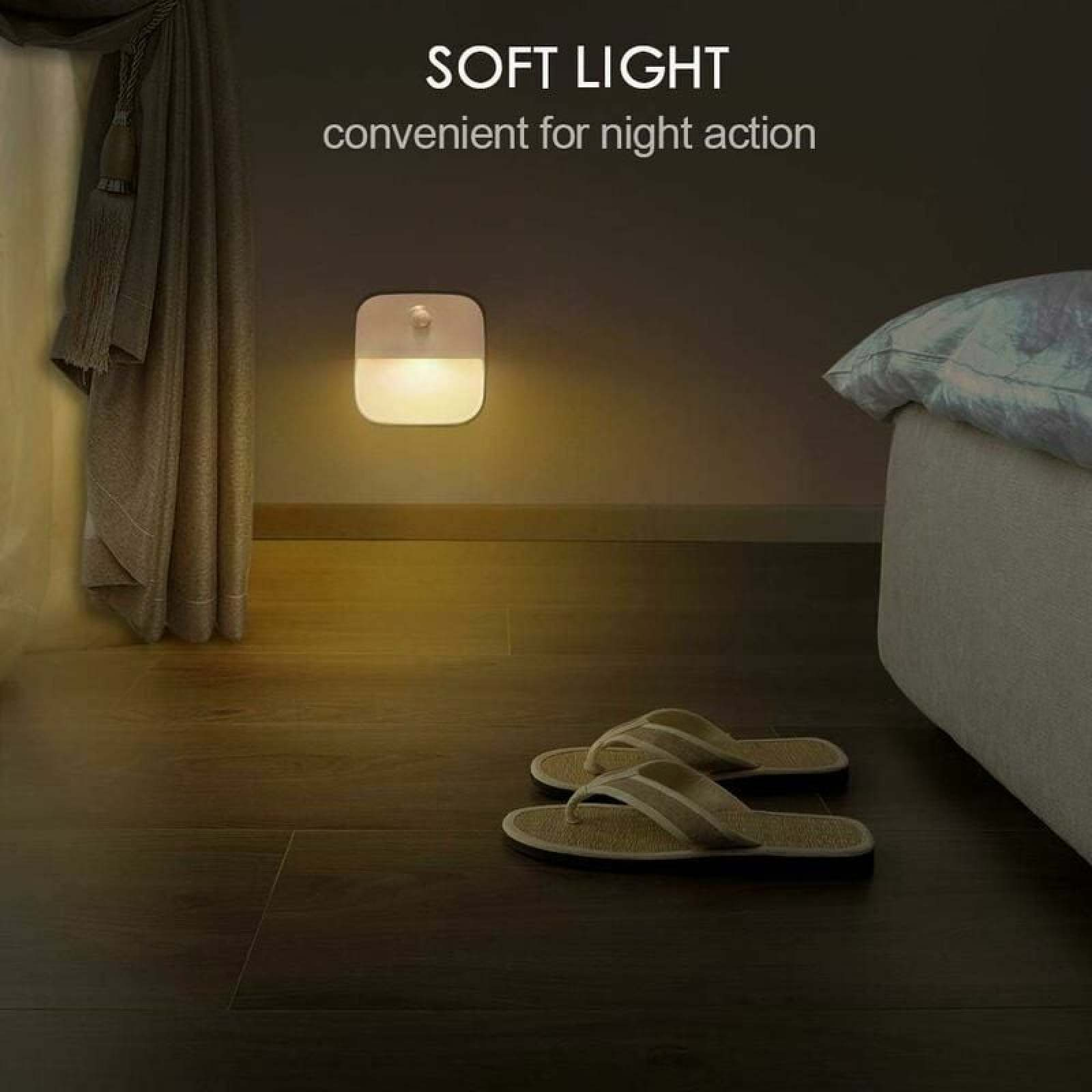 Ein kleines Nachtlicht leuchtet warm an einer Wand in einem abgedunkelten Schlafzimmer neben einem Bett.