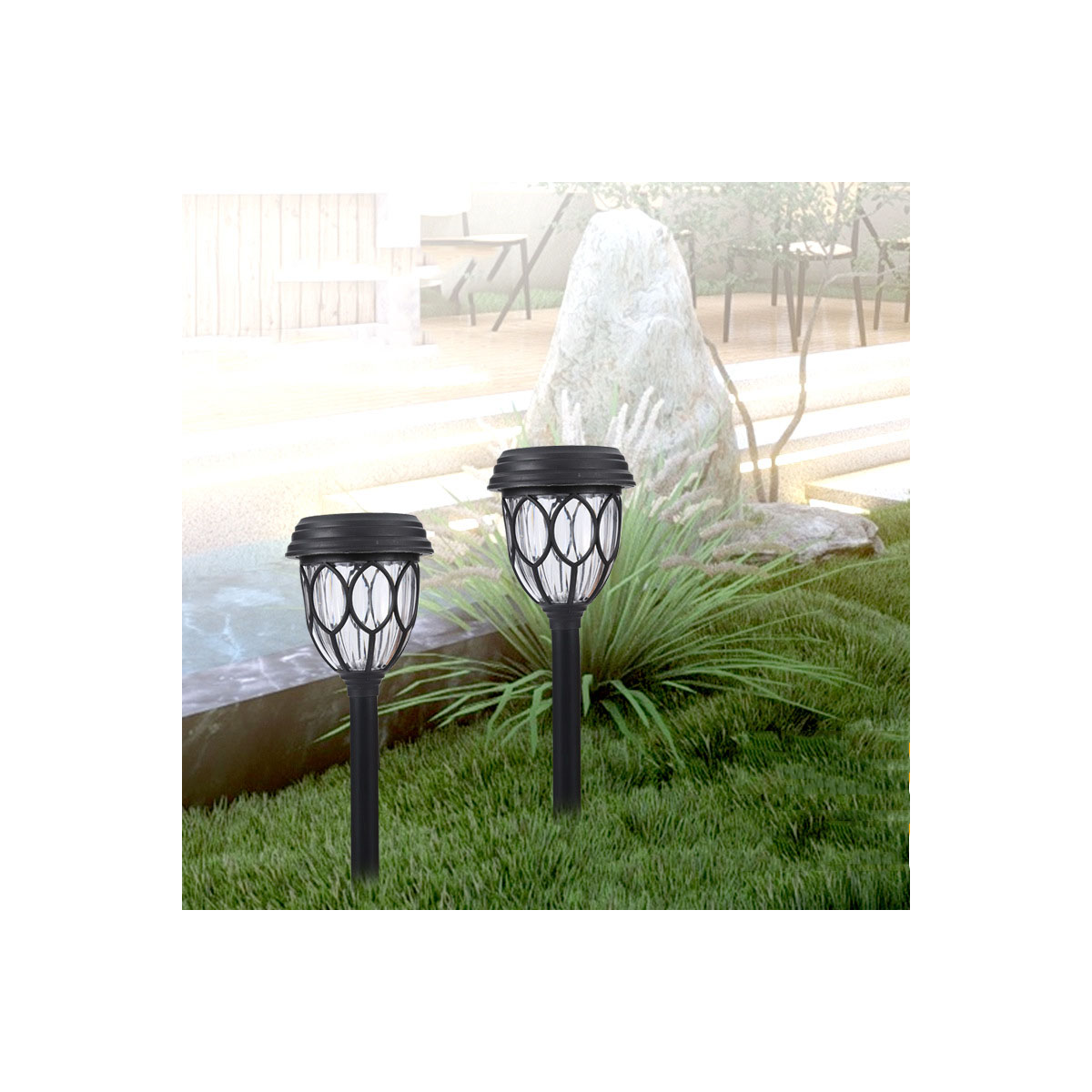 Zwei schwarze Solarlampen stehen in einem grünen Garten vor einem großen Stein und Pflanzen.