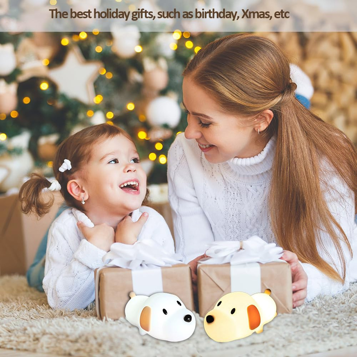 Eine Frau und ein Mädchen lächeln neben Geschenken, mit zwei Hundelichtern und einem beleuchteten Weihnachtsbaum.