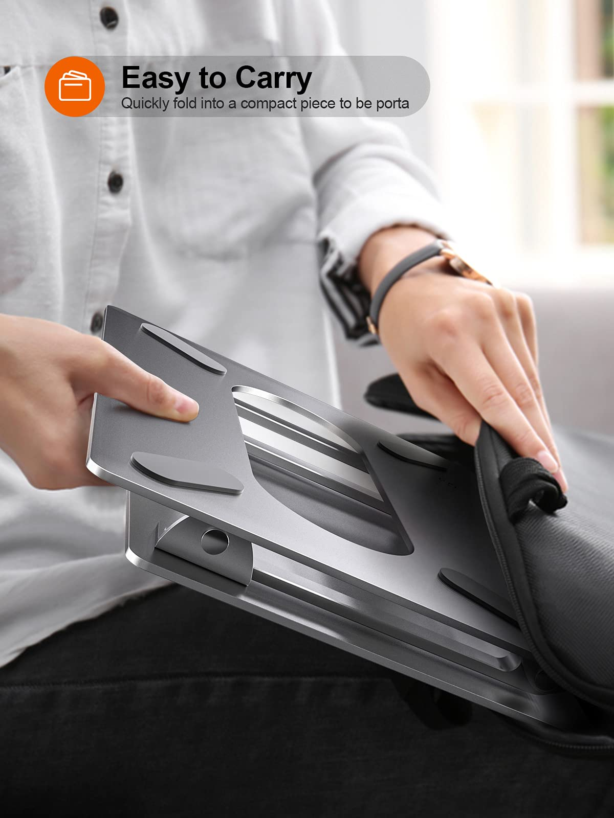 Eine Person legt einen faltbaren Laptopständer in eine Tasche.