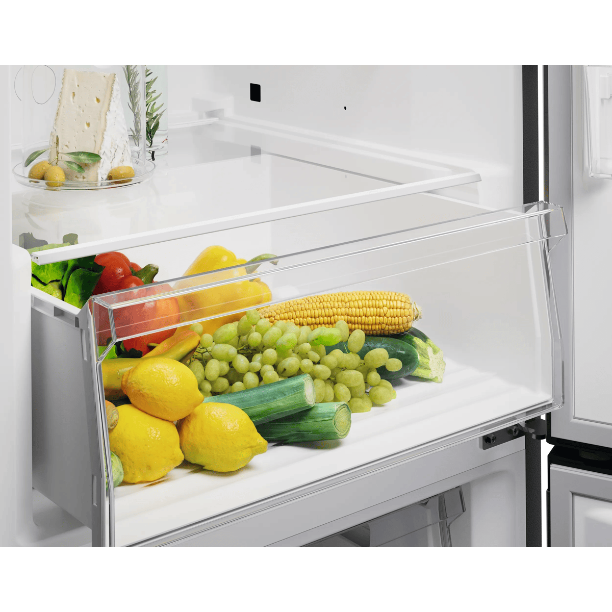 Un cajón para verduras de refrigerador lleno de frutas y verduras frescas como limones, maíz, uvas y pimientos.
