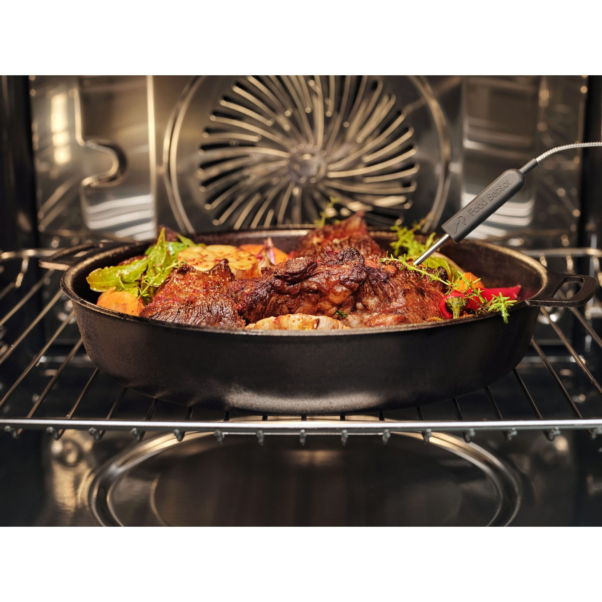Una fuente con carne y verduras está en el horno, un termómetro insertado en la carne.