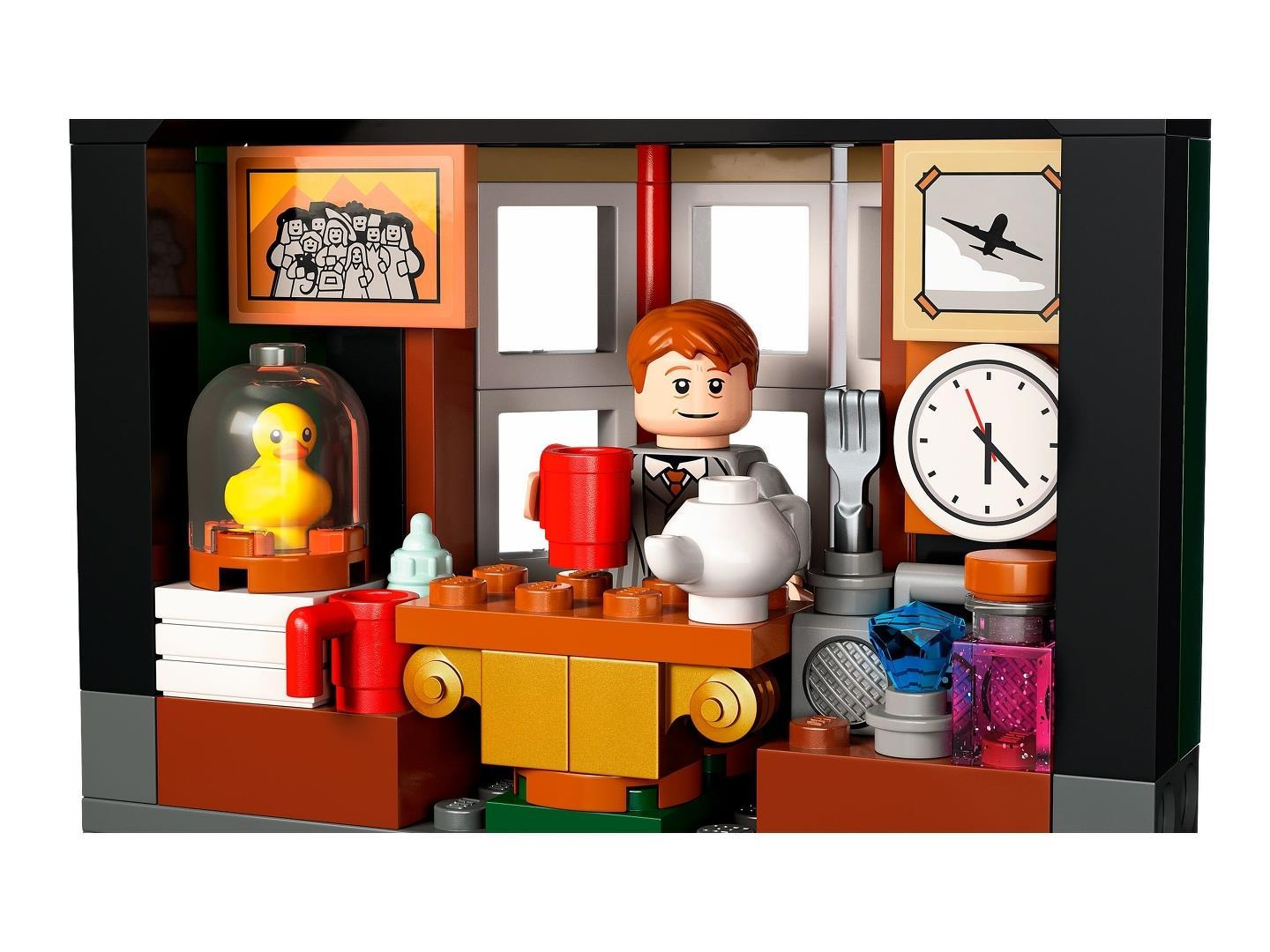 Ein Lego-Zimmer zeigt eine Minifigur mit rotem Becher, einen Tisch mit Teekanne, eine Ente und eine Wanduhr.