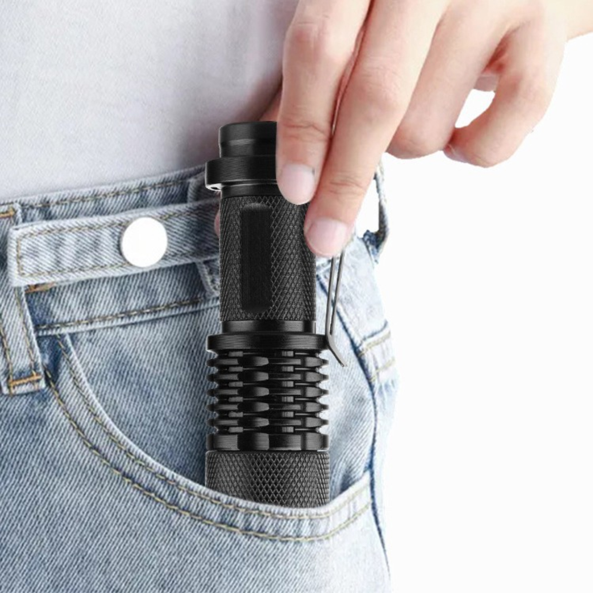 Eine Person steckt eine schwarze Taschenlampe in die Tasche ihrer blauen Jeans.