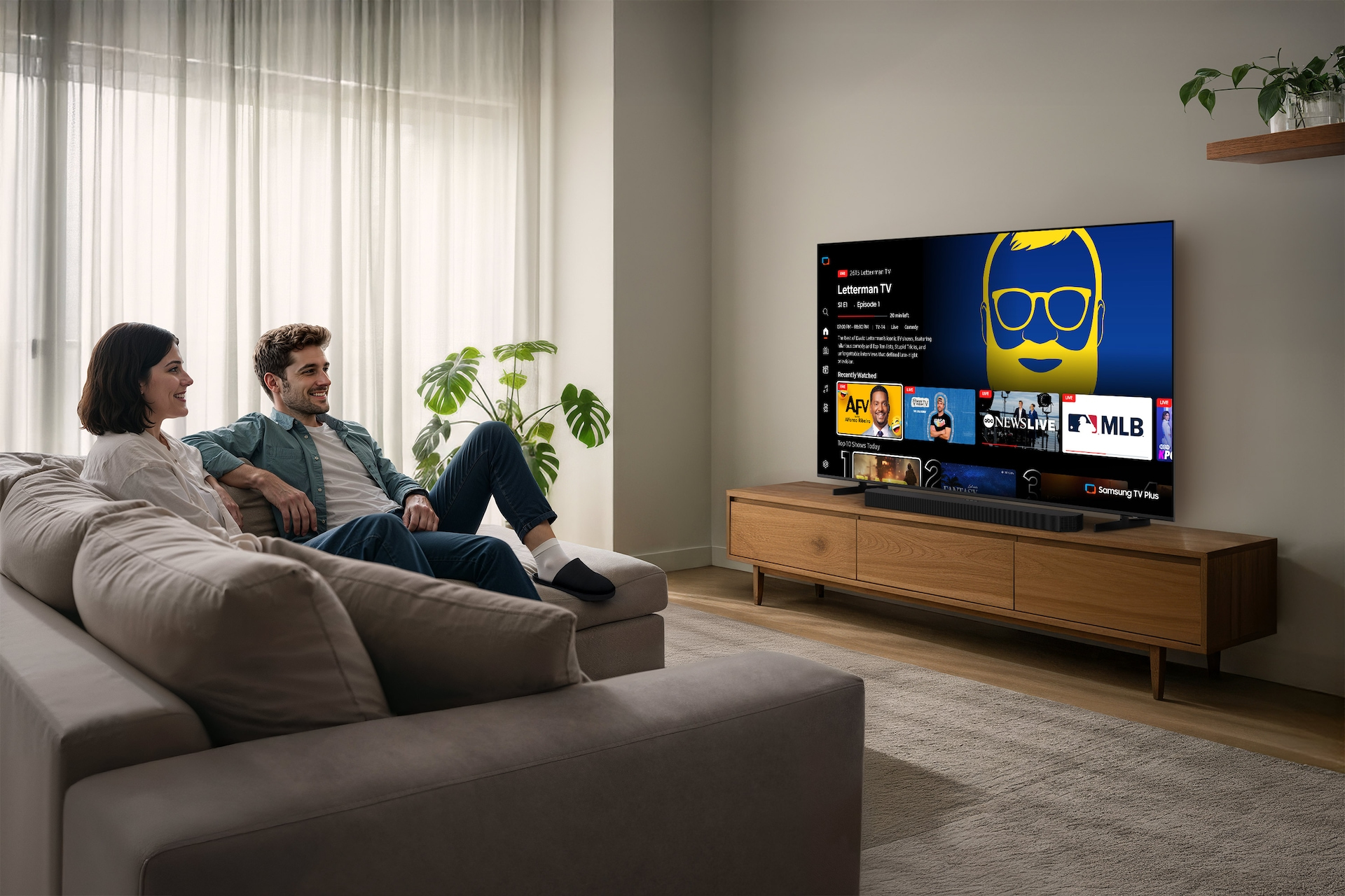 Una pareja se sienta en un sofá en una sala moderna viendo la televisión.