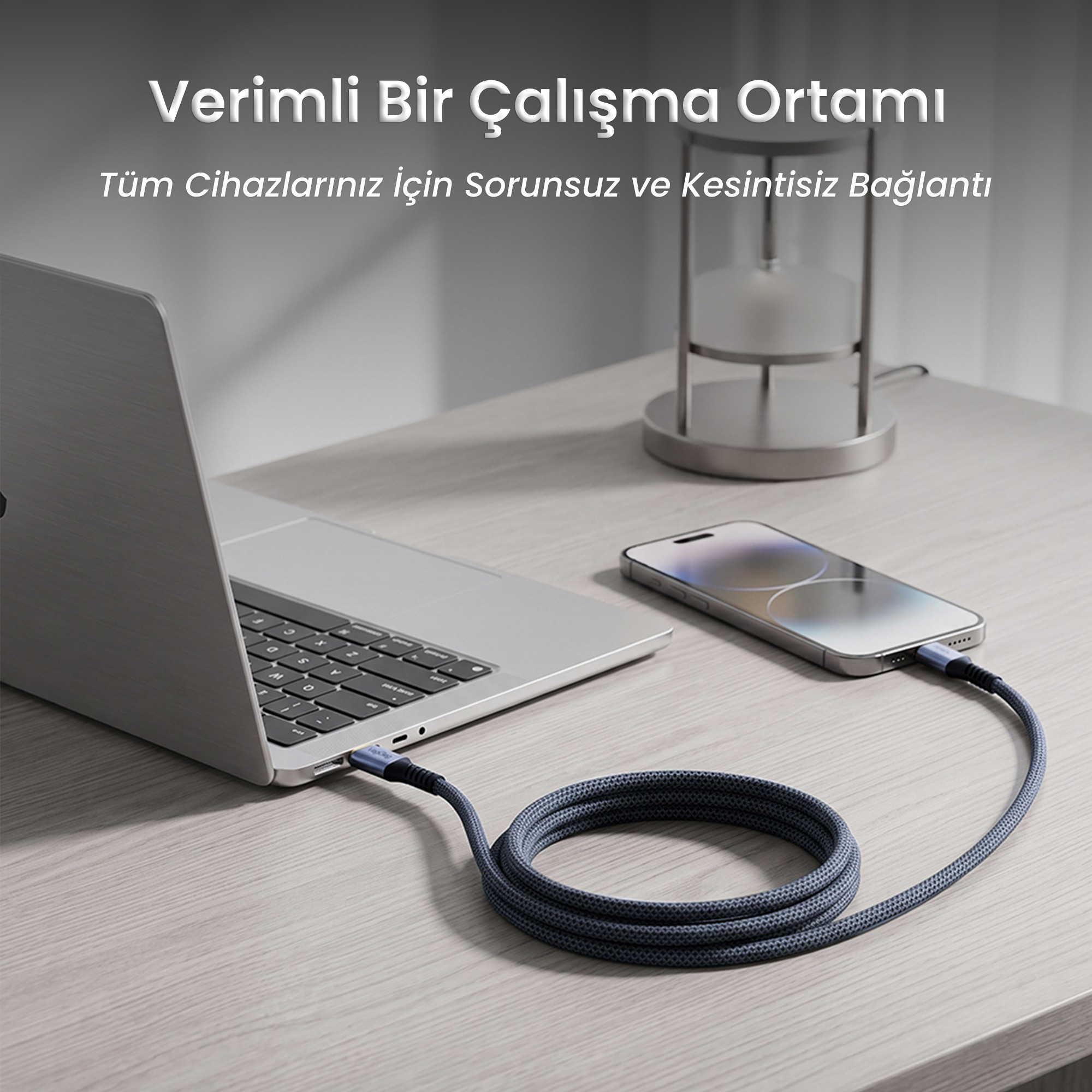 Ahşap masada bir dizüstü bilgisayarı akıllı telefona bağlayan gri örgü kablo.