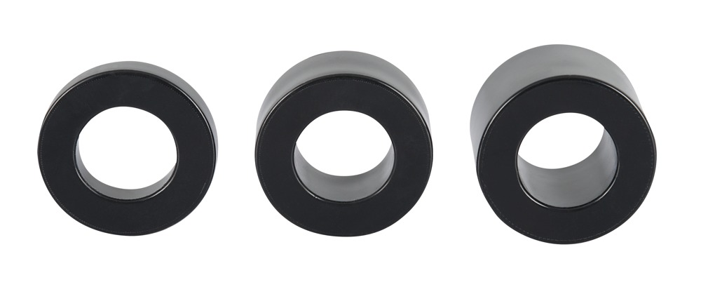 Drei schwarze zylindrische Ringe mit Mittelöchern, in einer Reihe auf weißem Hintergrund.