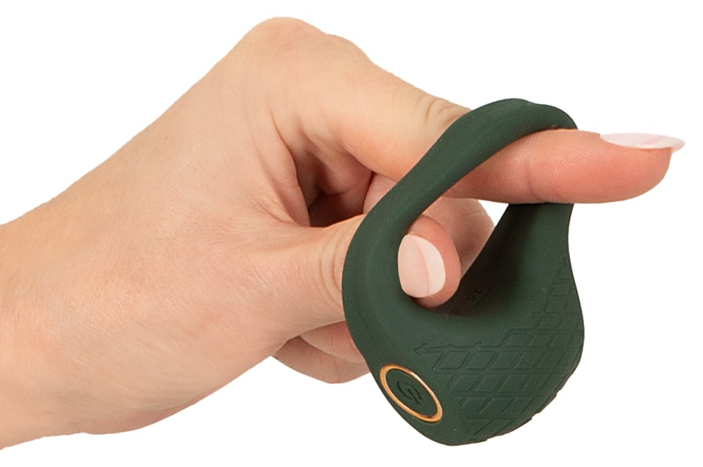 Eine Hand hält einen dunkelgrünen, ergonomischen Silikonring mit einem goldenen Power-Knopf auf weißem Hintergrund.