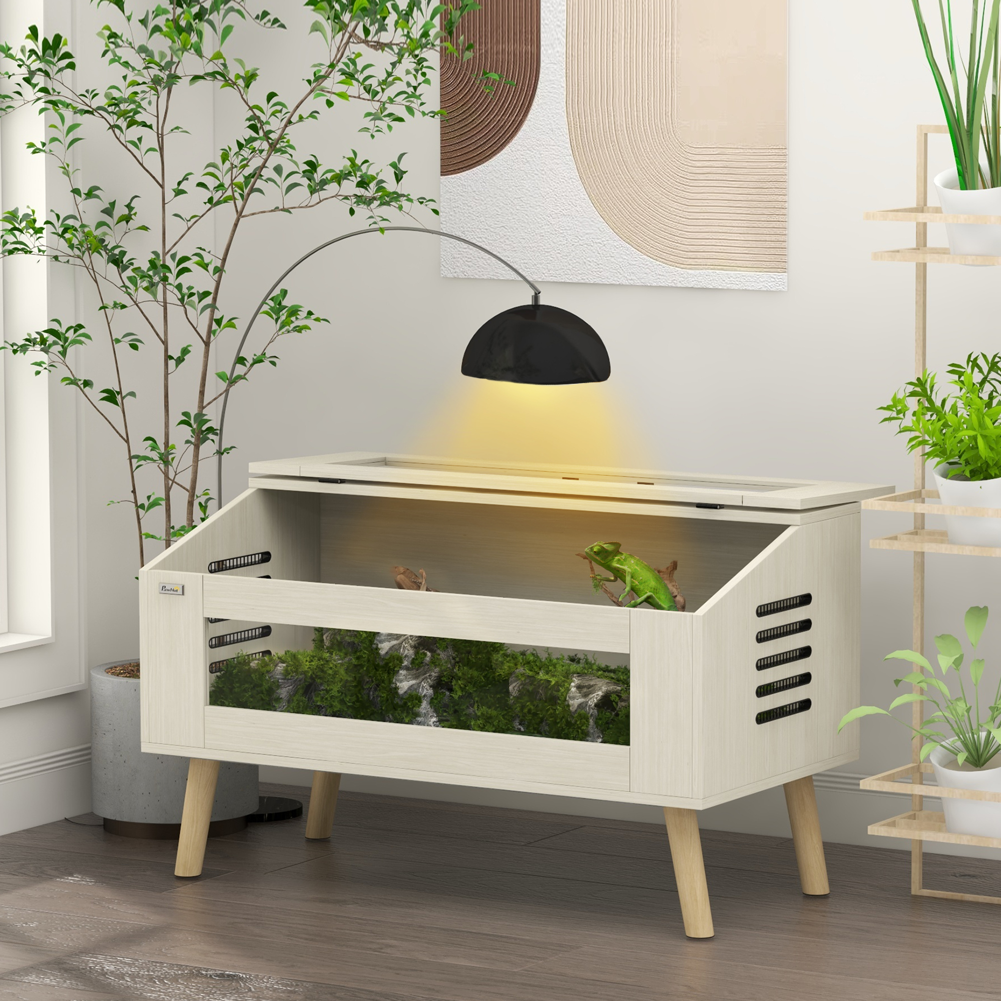 Un terrario de madera con camaleón verde, lámpara arriba y plantas al fondo.