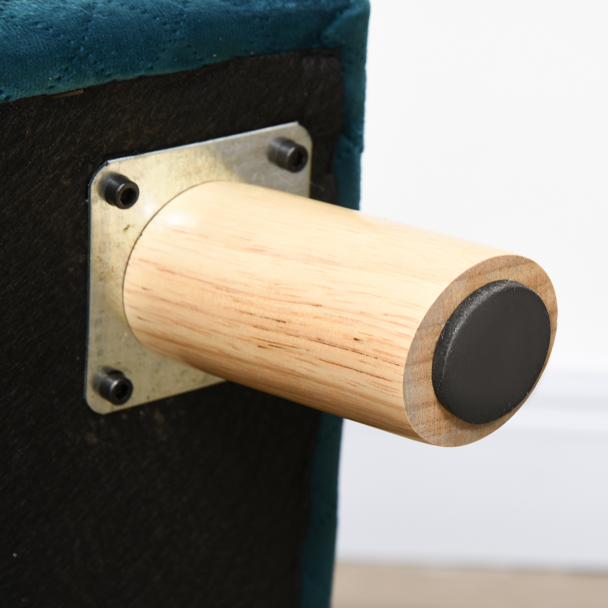Pata de mueble de madera con placa metálica y almohadilla de goma negra en la parte inferior del sofá azul.