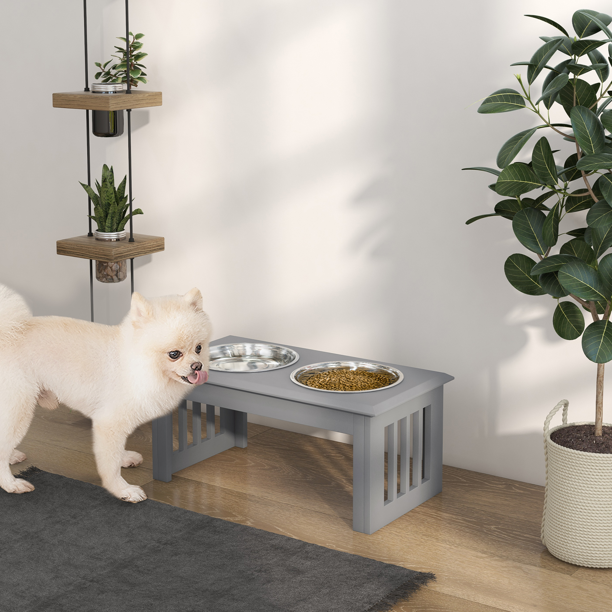 Un perro blanco pequeño está cerca de un comedero gris con dos cuencos en suelo de madera.