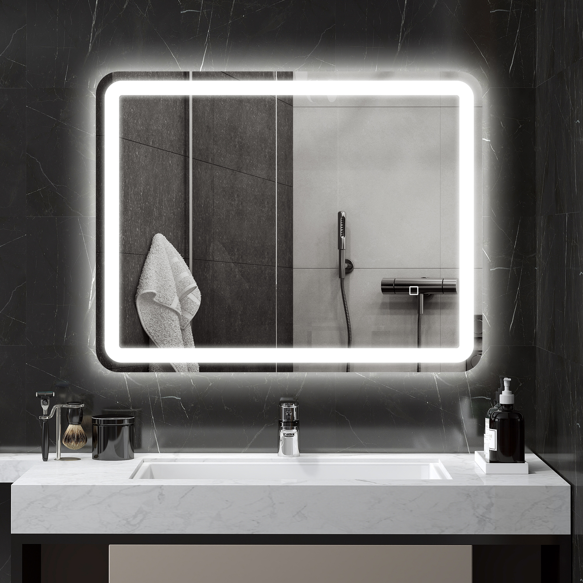 Espejo de baño iluminado sobre un lavabo contra una pared de mármol negro.