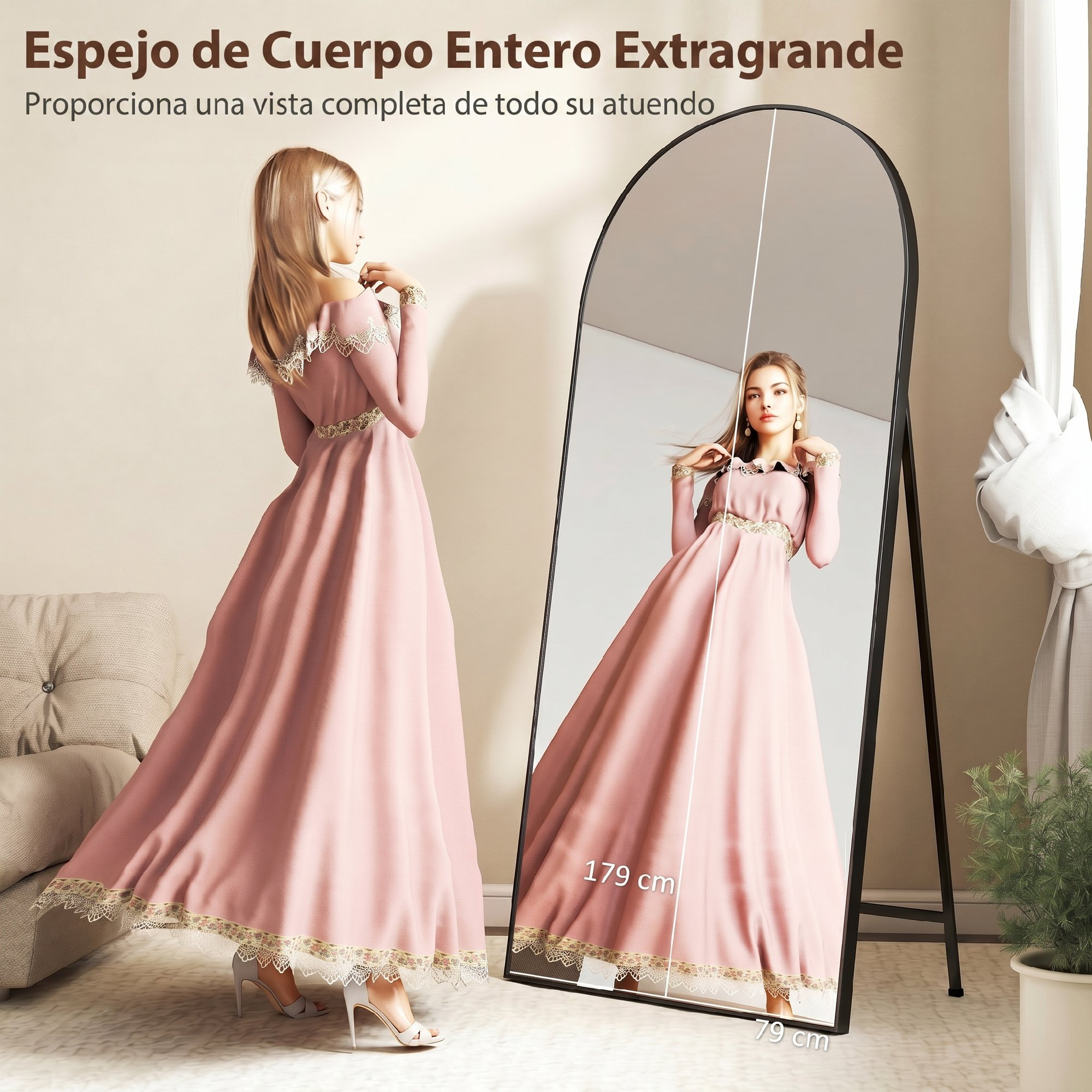 Una mujer con un vestido largo rosa frente a un gran espejo arqueado de cuerpo entero en una habitación.
