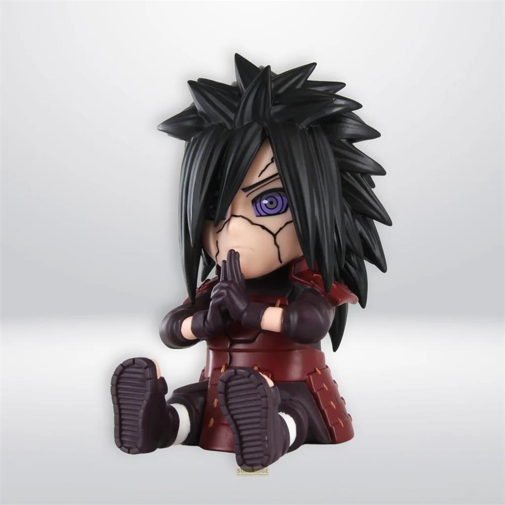 Una figura chibi de Madara Uchiha con largo cabello negro, ojos morados y armadura roja está sentada en el suelo.
