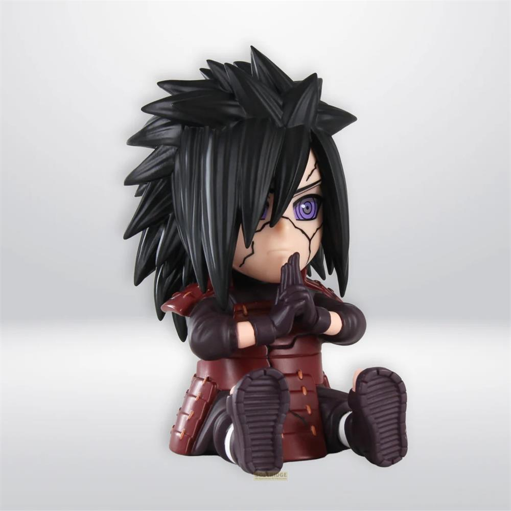 Una figura de anime estilo chibi con cabello negro puntiagudo, ojos rinnegan morados y armadura roja está sentada con las manos juntas.