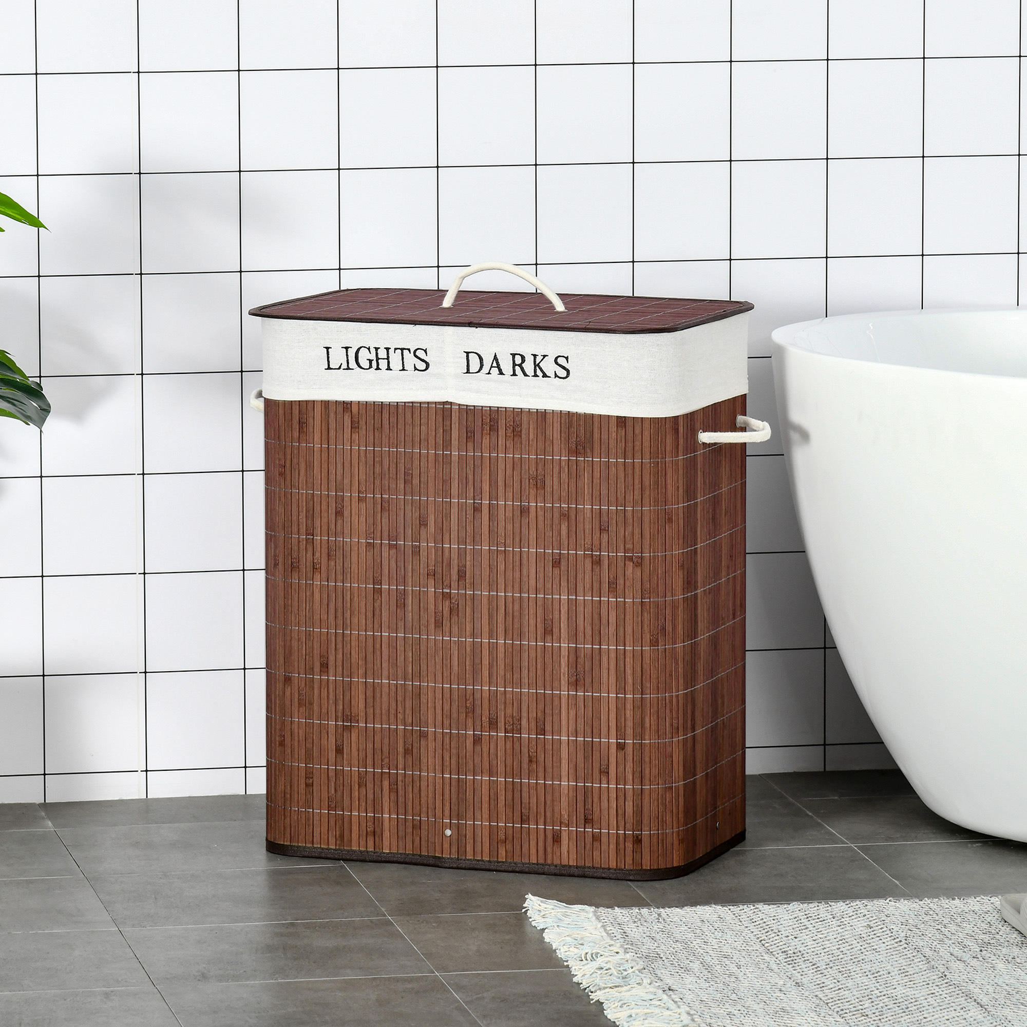 Un cesto de ropa rectangular de bambú marrón con etiquetas LIGERO OSCURO en un baño de azulejos blancos.