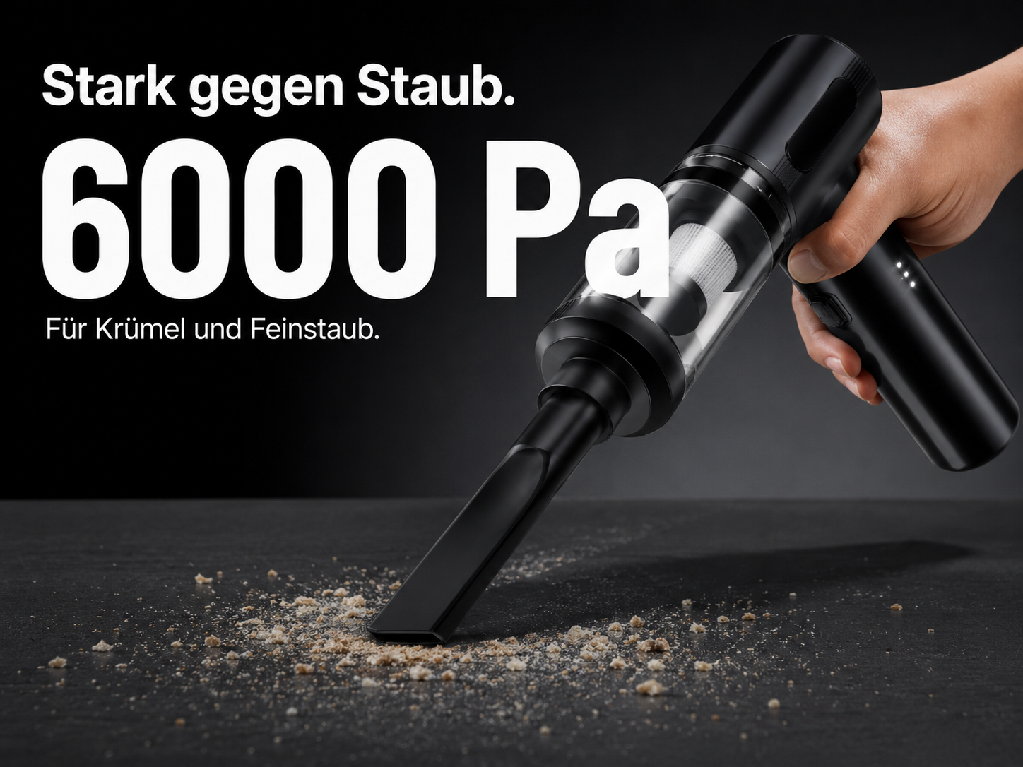 Handstaubsauger saugt Krümel von einer dunklen Oberfläche auf.