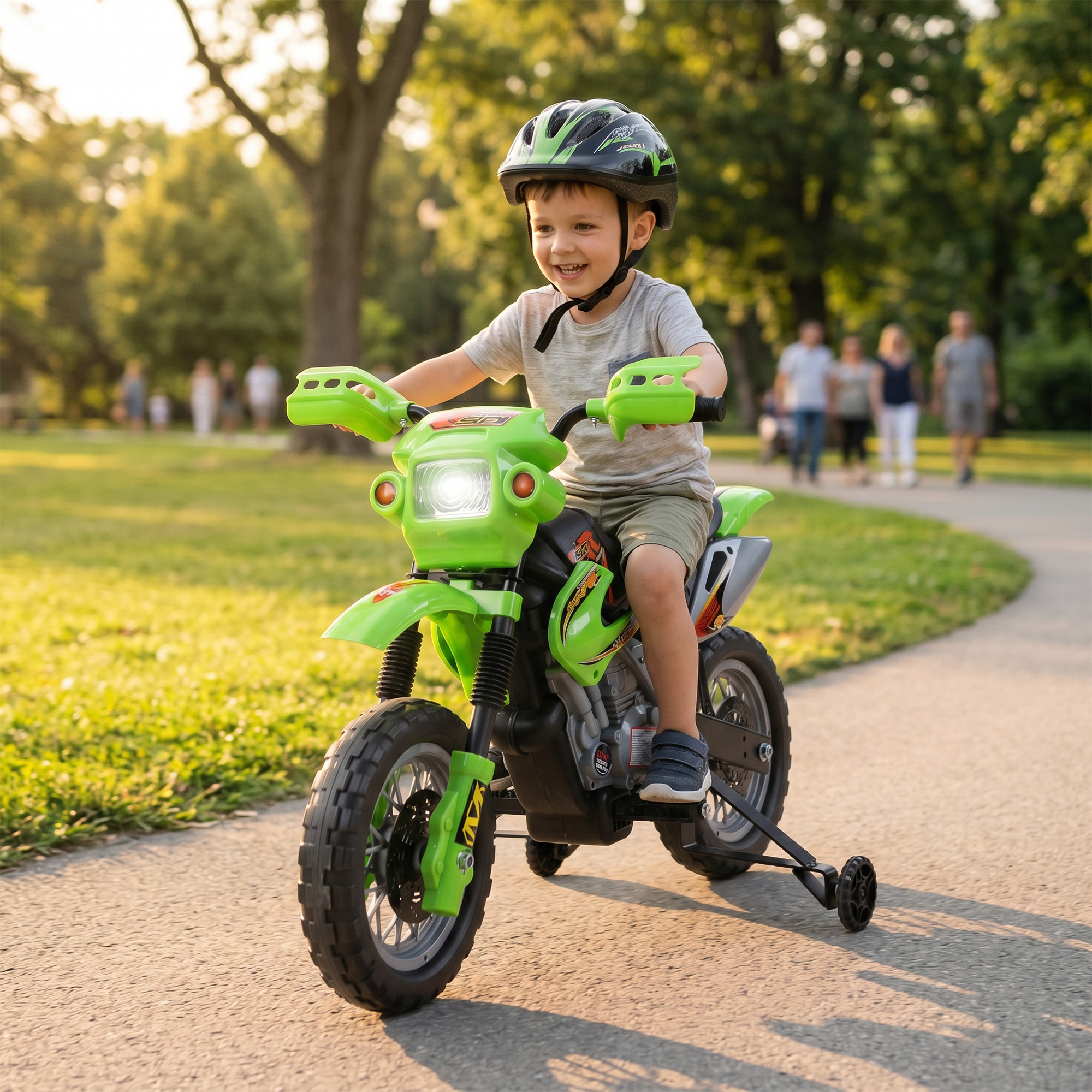 Un niño con casco monta en una moto de juguete verde por el parque.