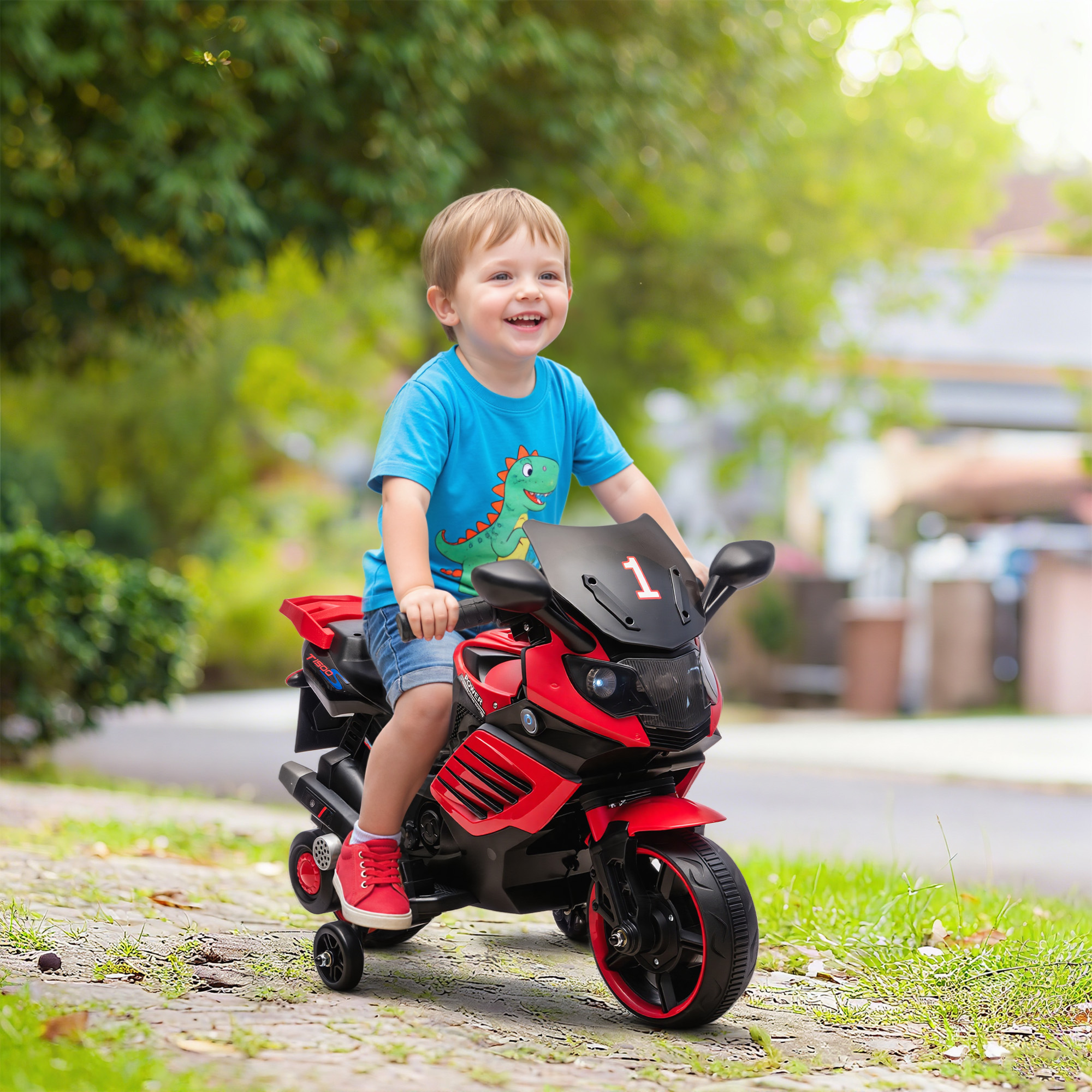 Niño sonriendo felizmente mientras monta en una motocicleta de juguete roja con ruedas de entrenamiento al aire libre.