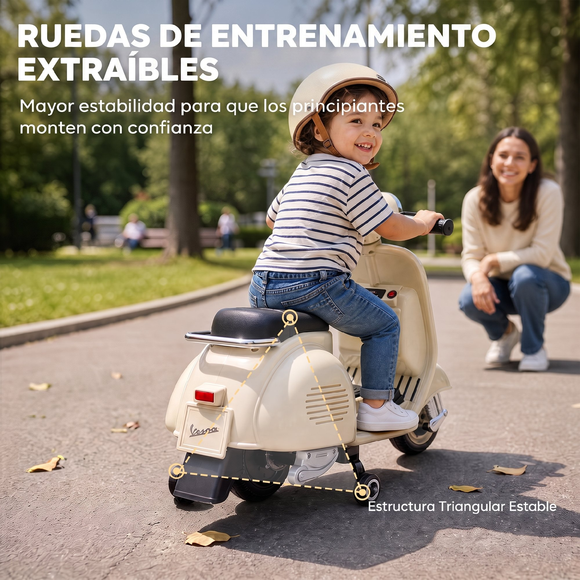 Un niño pequeño monta en un patinete de juguete beige con ruedas de entrenamiento en un parque mientras una mujer observa.
