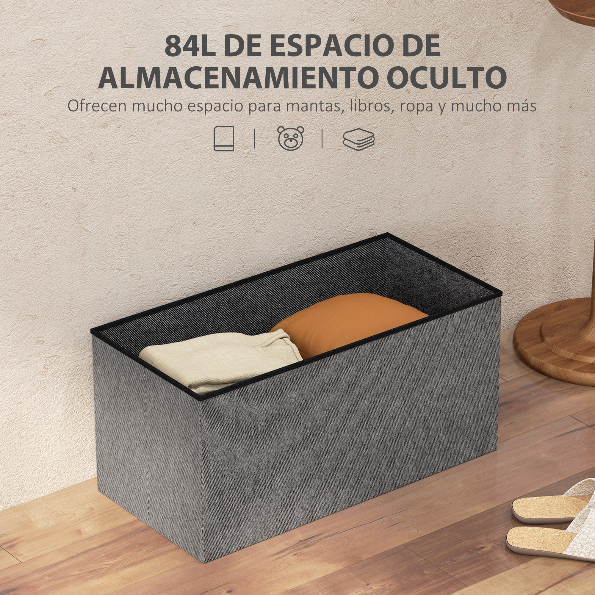 Caja de almacenamiento de tela gris con mantas en suelo de madera y pared beige.